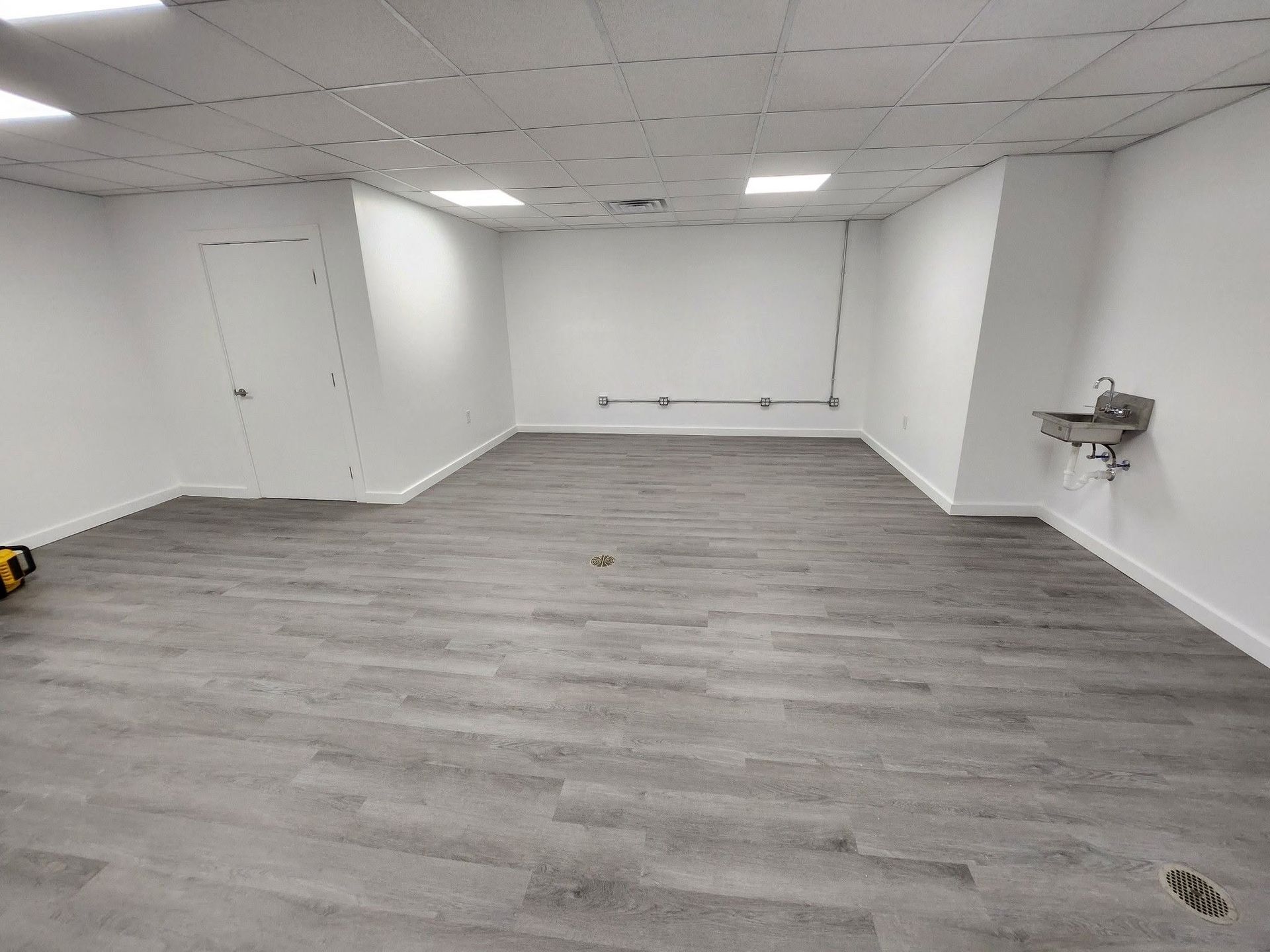Empty white room with gray wood-look flooring and recessed ceiling lights