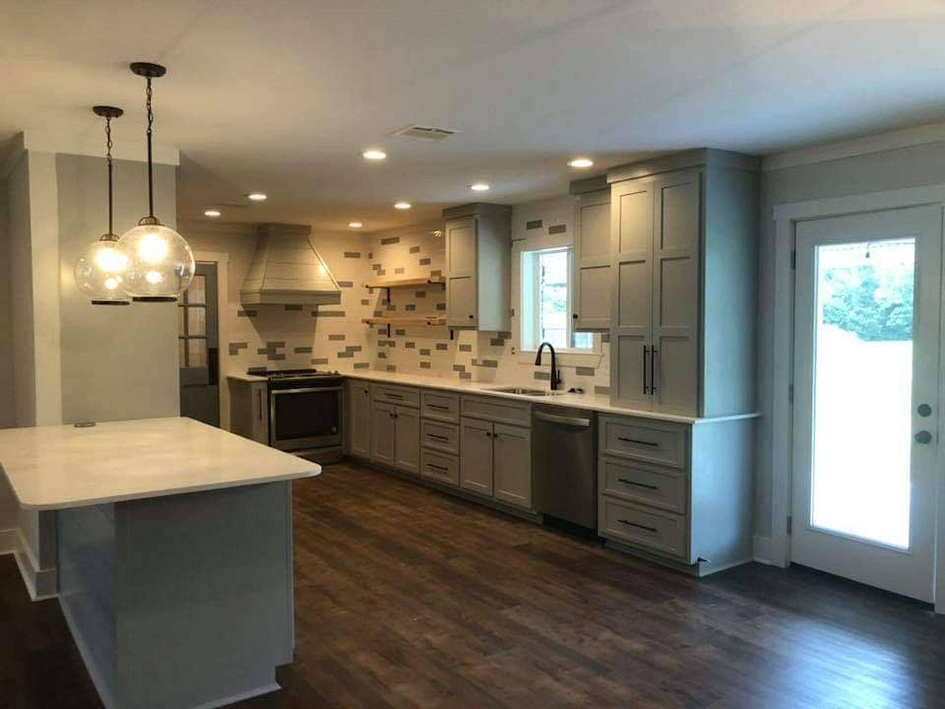 Modern kitchen with dark wood floors, gray cabinets, island, and pendant lights