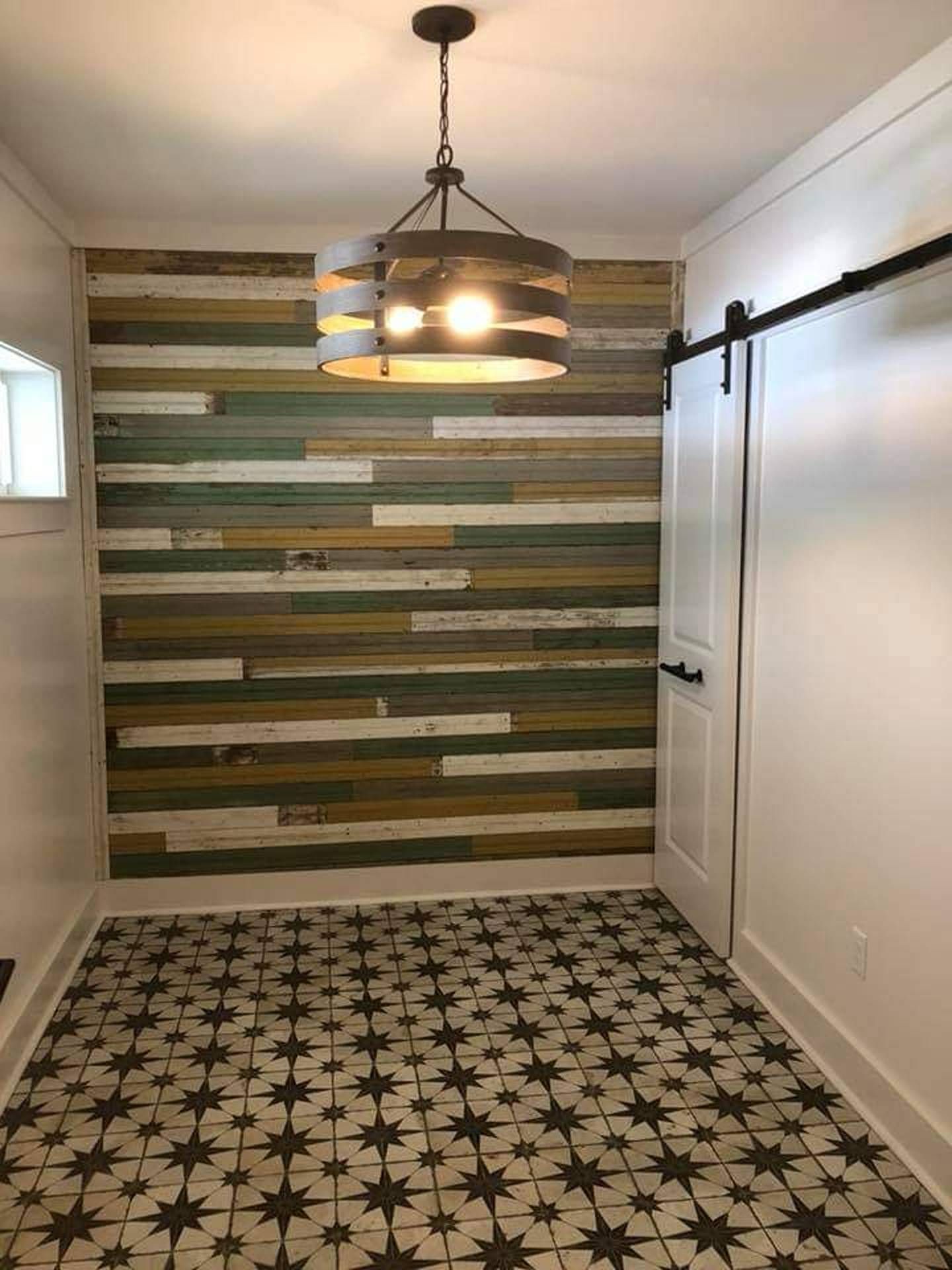 Narrow hallway with patterned tile floor, wood accent wall, and hanging light fixture.