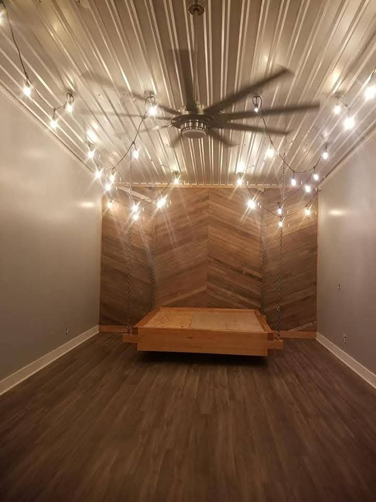 String lights over a wood-paneled nook with a wooden bench and ceiling fan in a cozy room