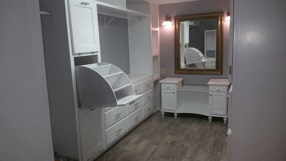 White bedroom vanity with drawers, mirror, and shelving in a small gray room