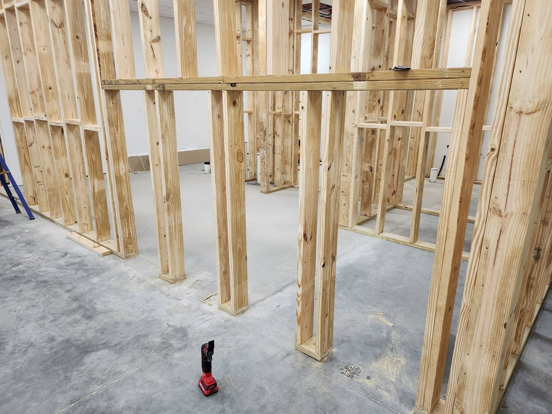 Framed interior of a house under construction with exposed wooden studs and a concrete floor