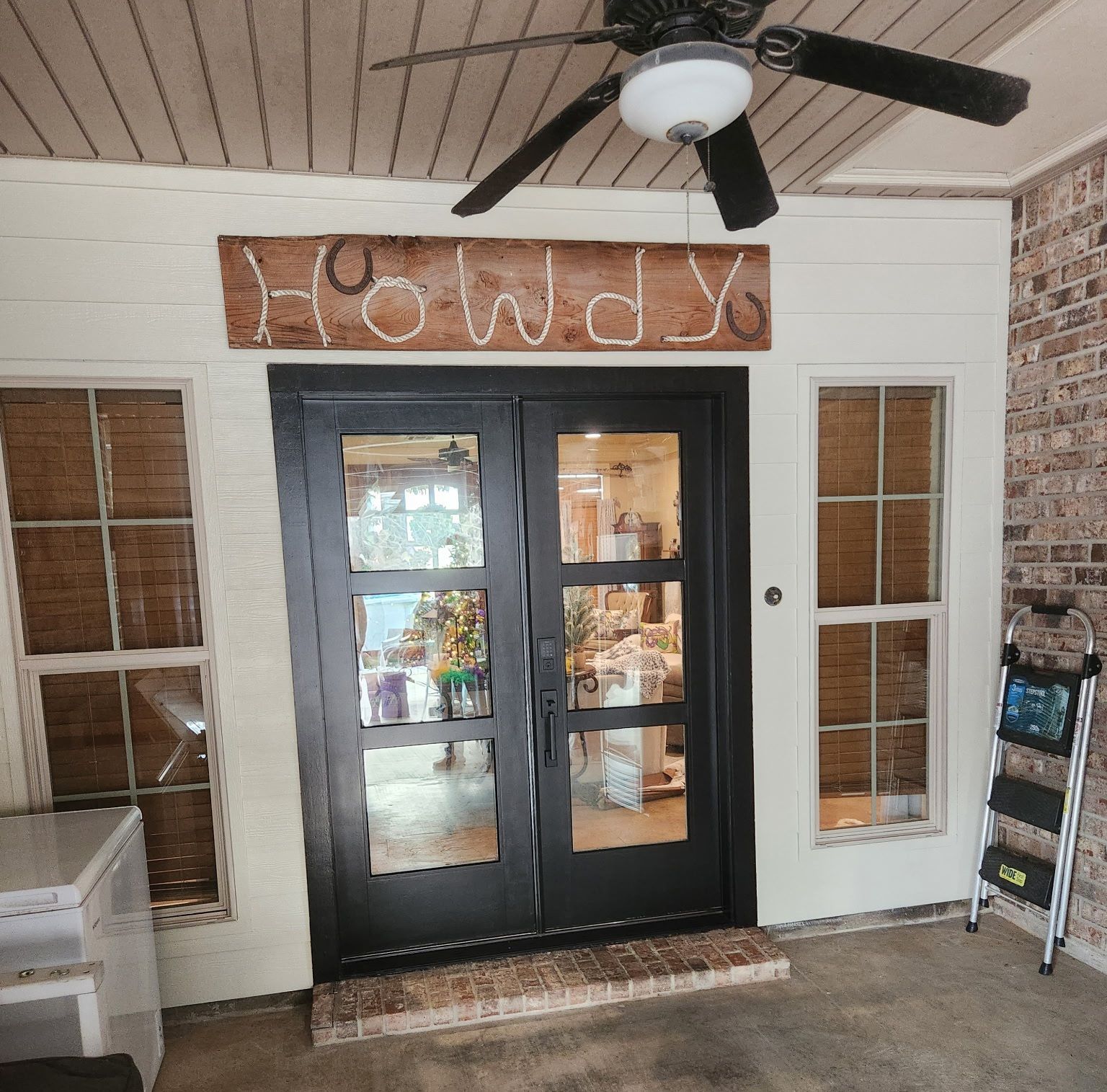 Black double doors on a storefront with a carved wooden sign above and brick walls around them