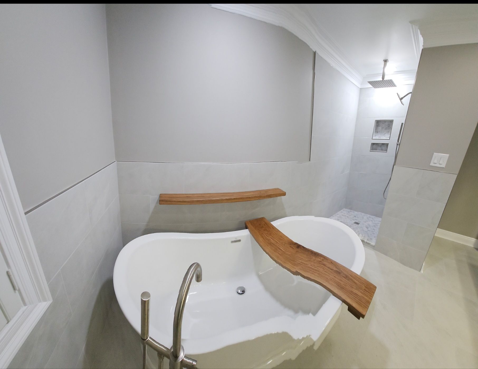 Accessible bathroom with a white tub, wooden transfer bench, and grab bars.