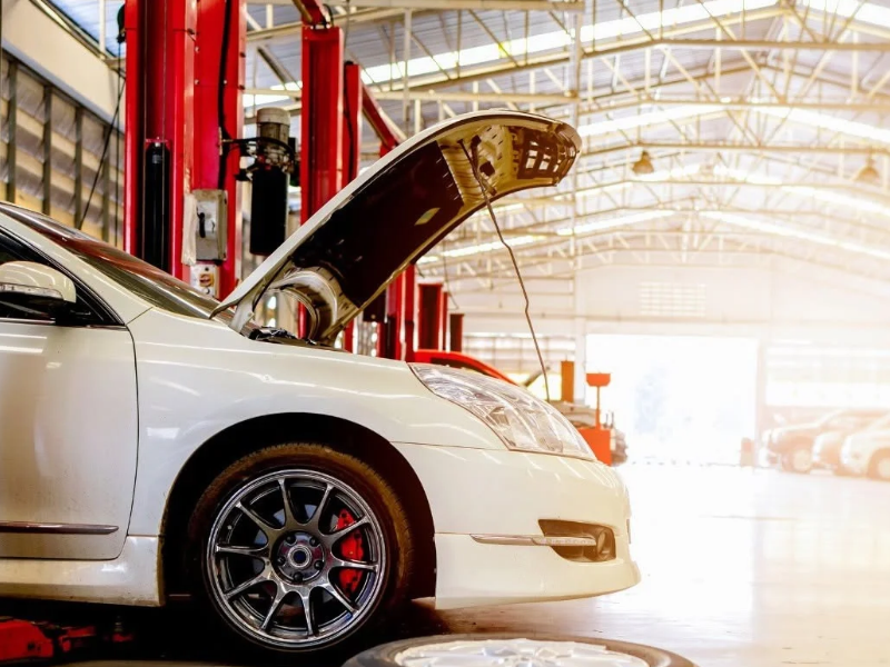 Mechanic working under a car on a lift, inspecting the undercarriage in a garage