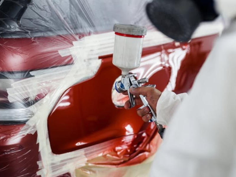 Hands polishing a white car&rsquo;s rear bumper with a yellow buffer pad