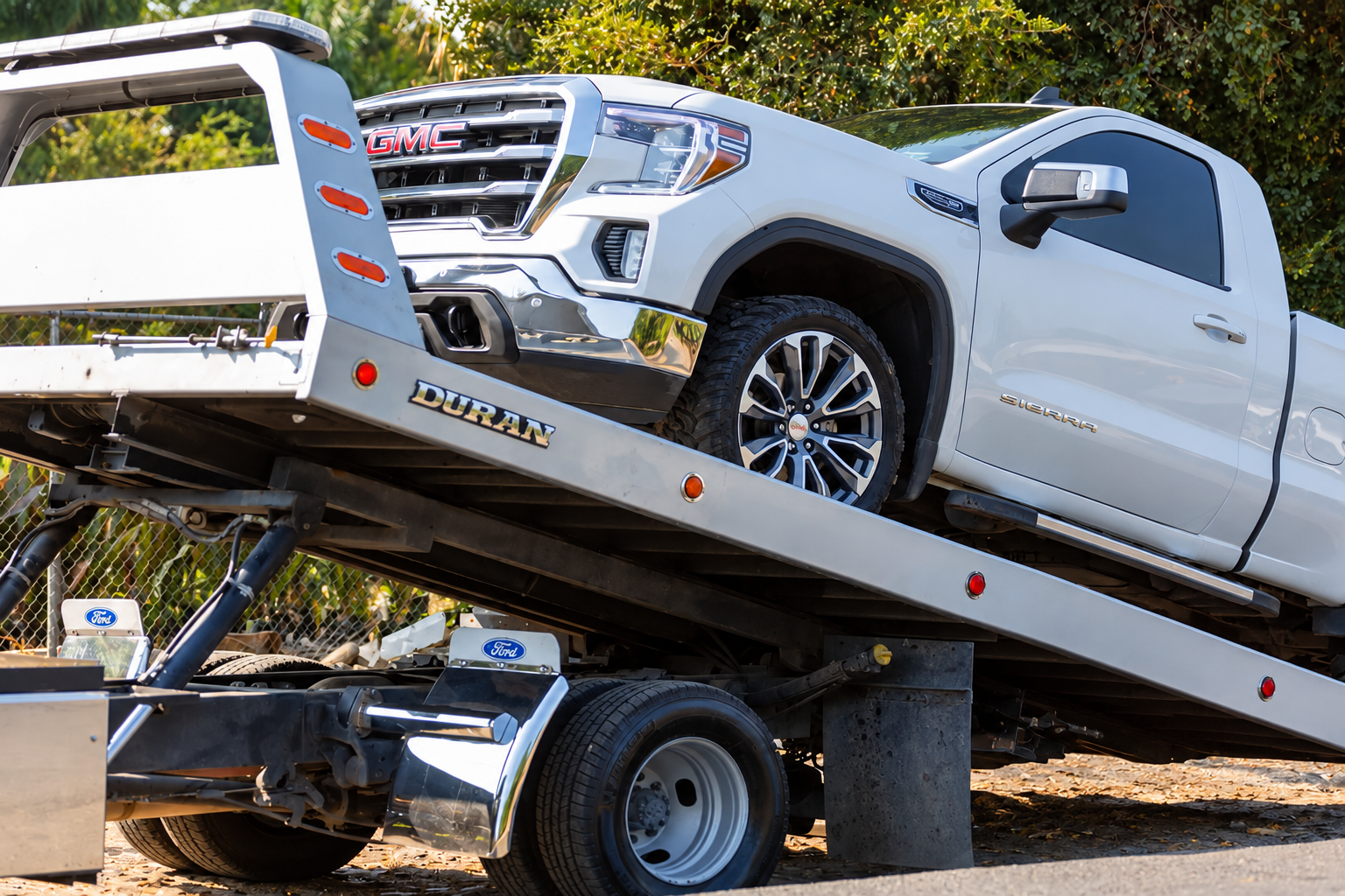 Flatbed tow truck carrying a white pickup truck