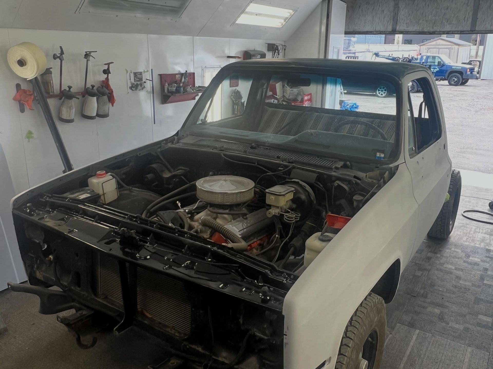 Classic pickup truck in a garage with its hood removed and engine exposed.