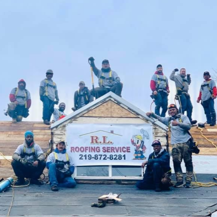 Roofing crew posing on a rooftop with an R.L. Roofing Service sign and phone number signboard.