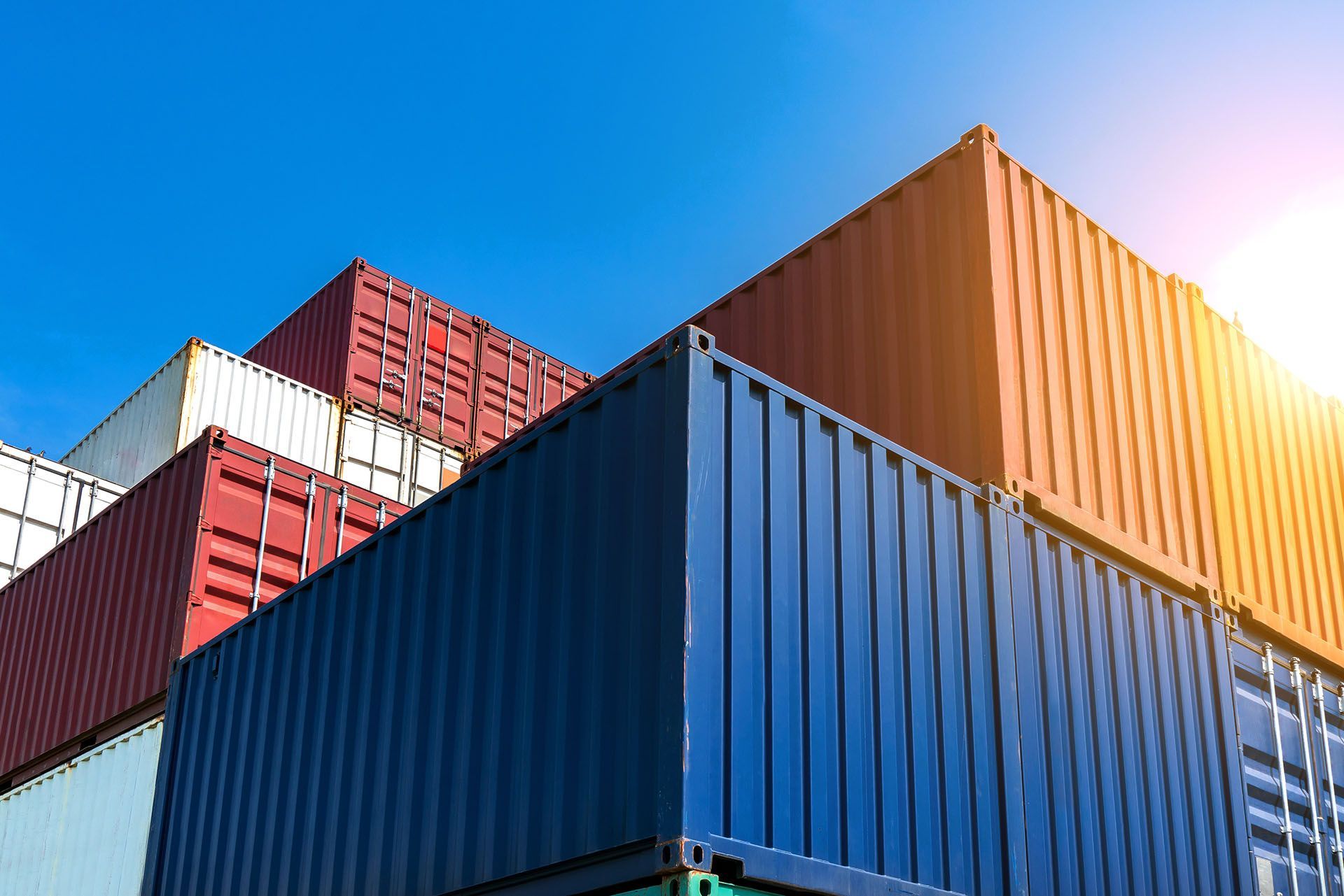 A stack of shipping containers against a blue sky.