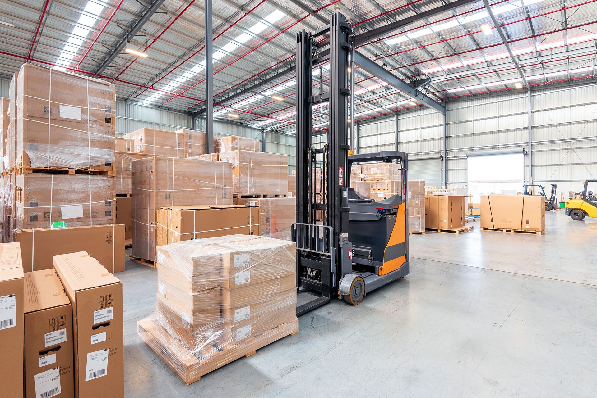 A forklift is moving boxes in a large warehouse.