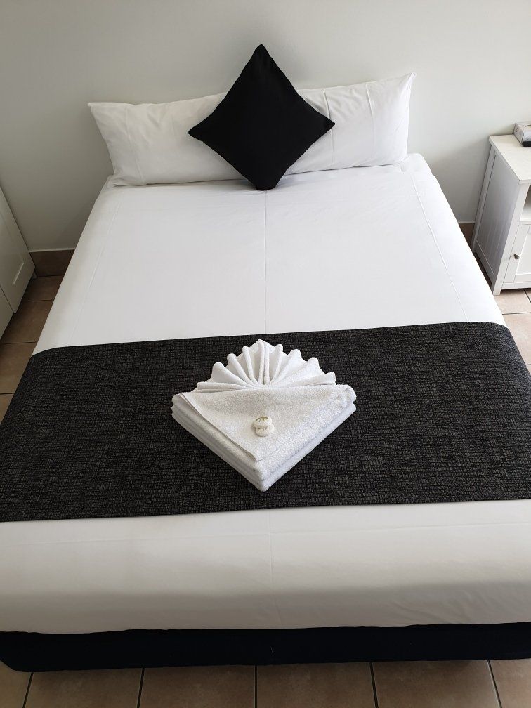 A Bed With White Sheets And A Black Blanket — Original North Australian in Bowen, QLD