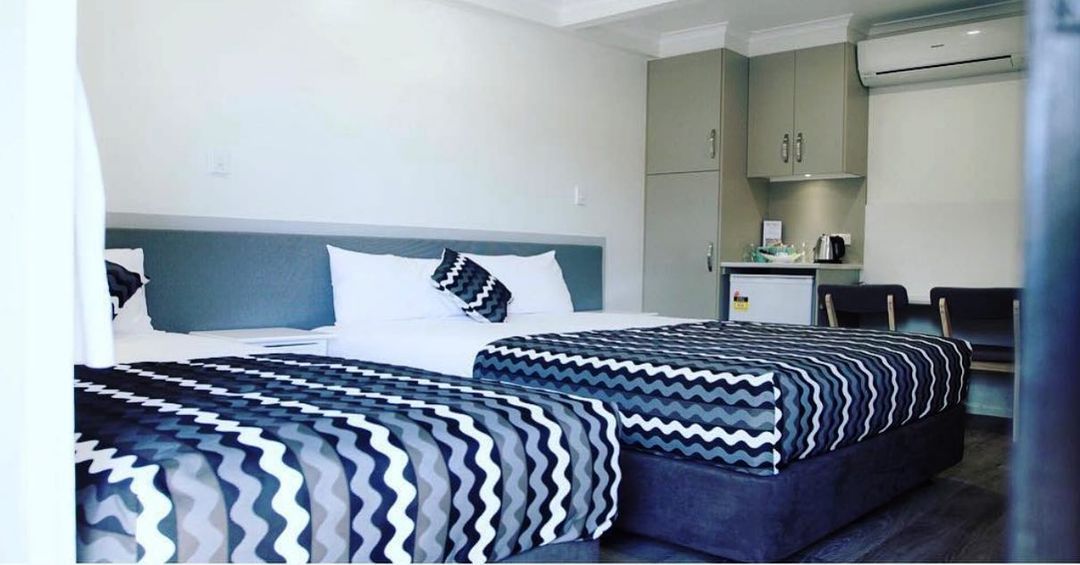 A Hotel Room With Two Beds And A Chair — Original North Australian in Bowen, QLD