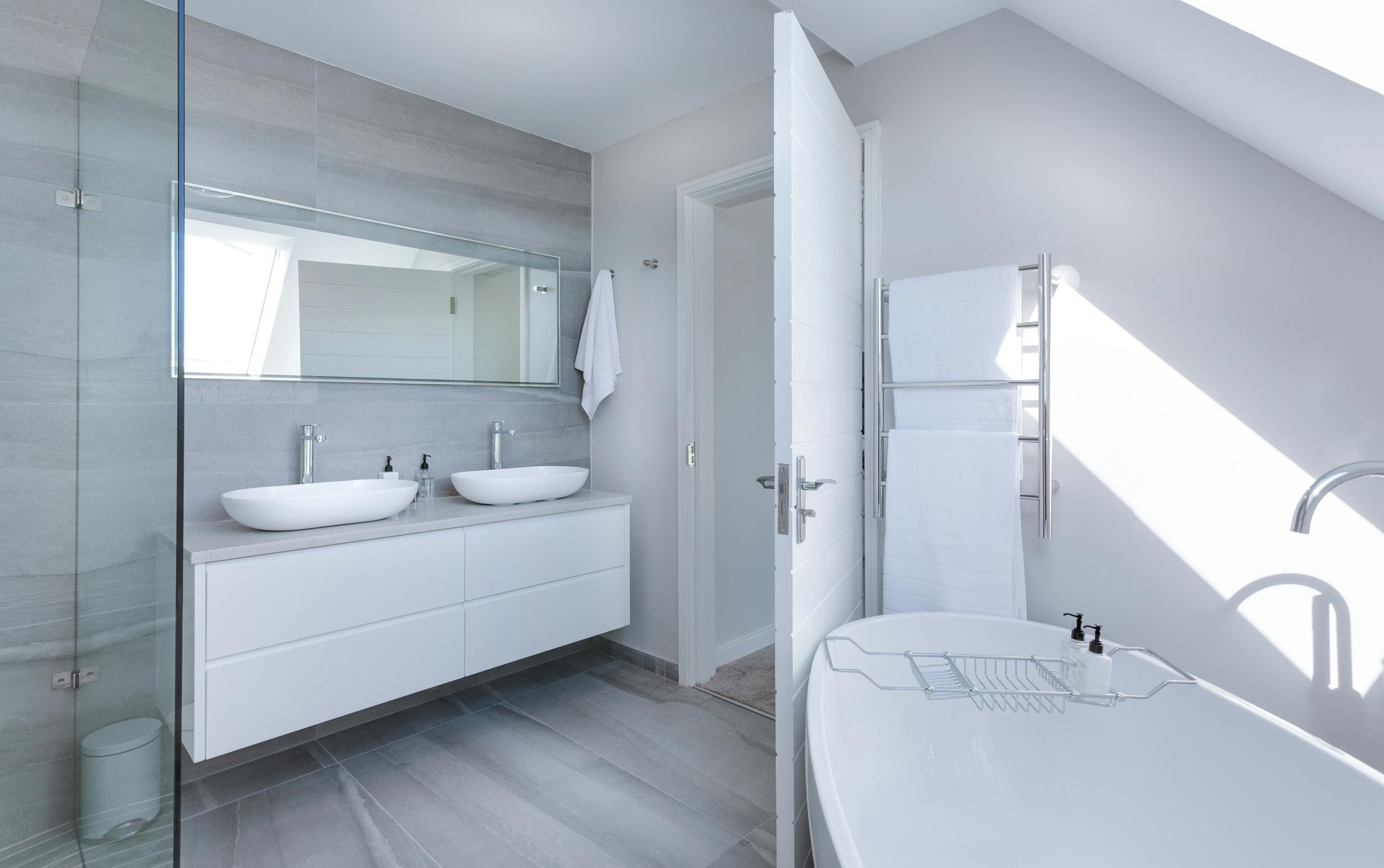 Bright modern bathroom with double sink vanity, wall mirror, shower, and freestanding tub