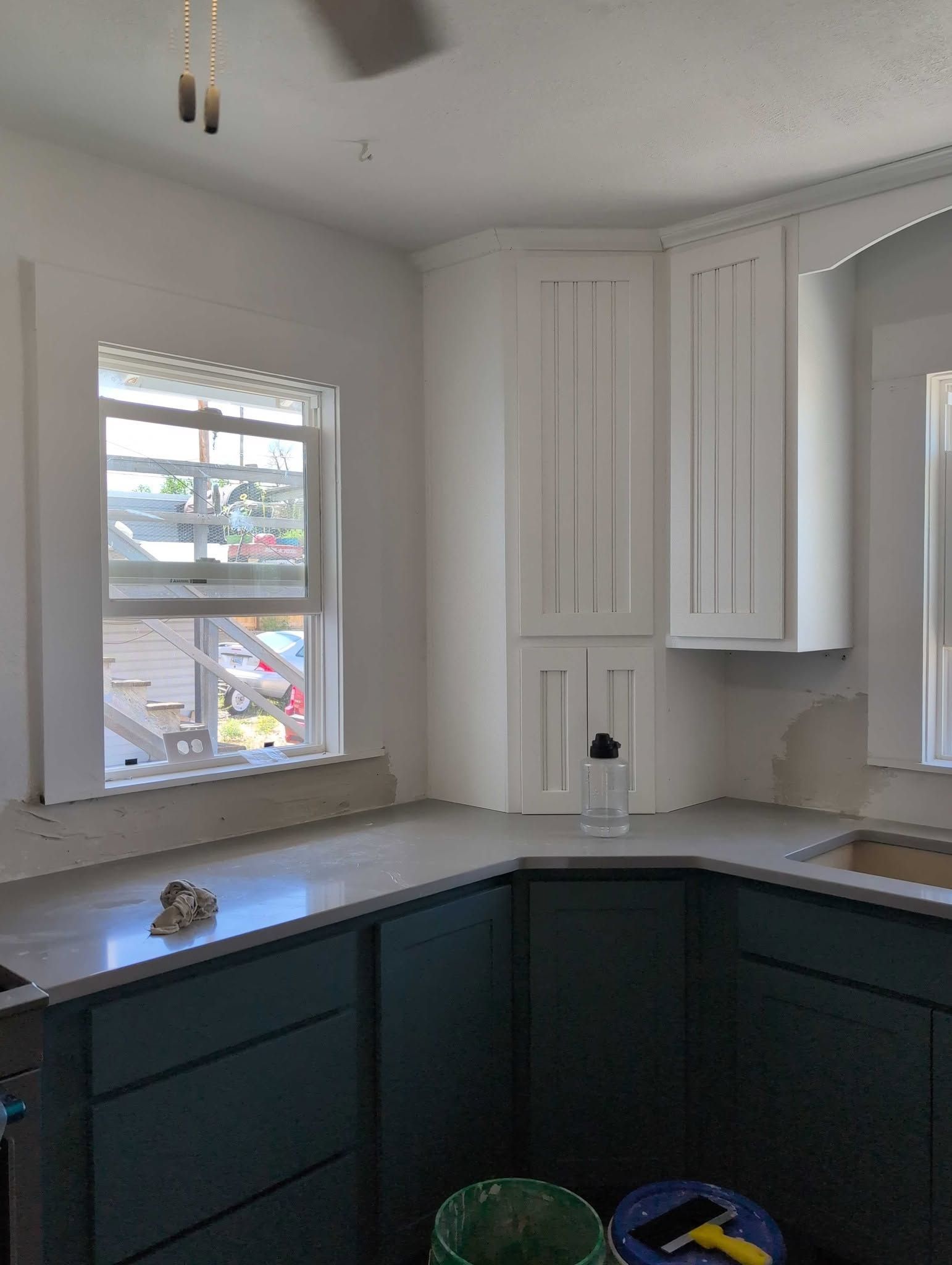 Small kitchen with white cabinets, dark lower cabinets, and a window overlooking parked cars.