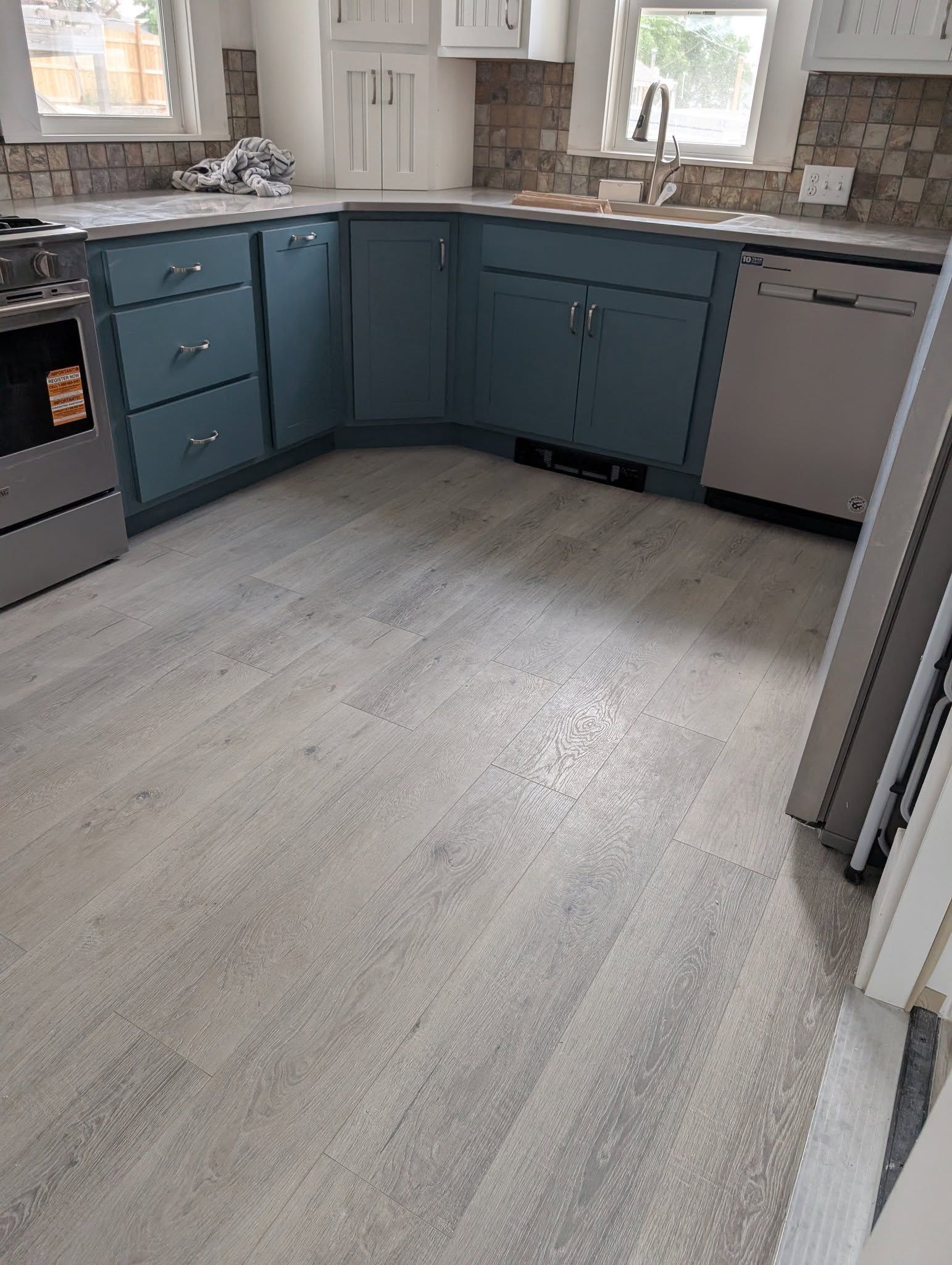 Modern kitchen with blue cabinets, gray countertops, stainless appliances, and light wood flooring