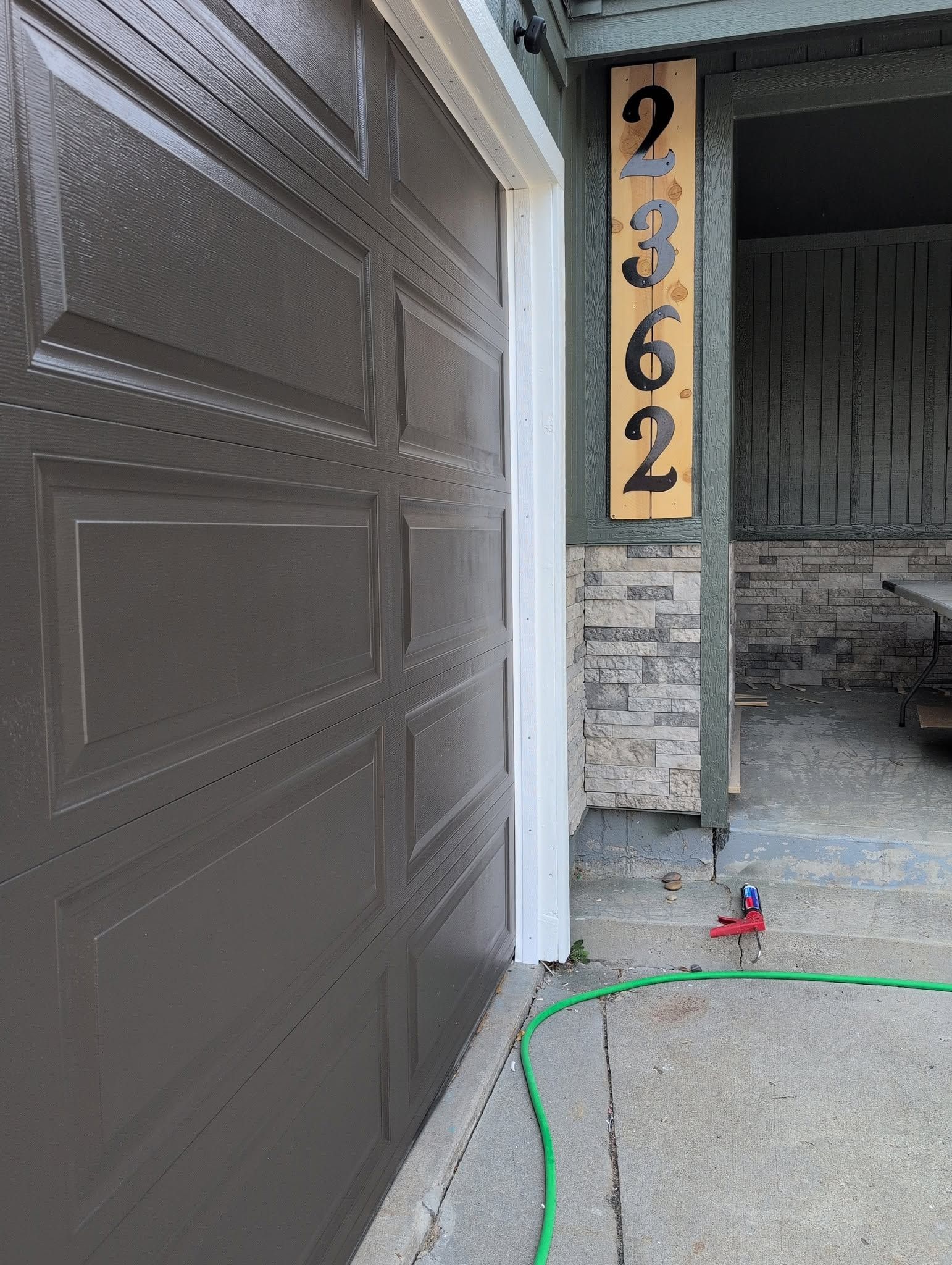 House garage entry with dark brown door, vertical address plaque 2362, and a small porch area.