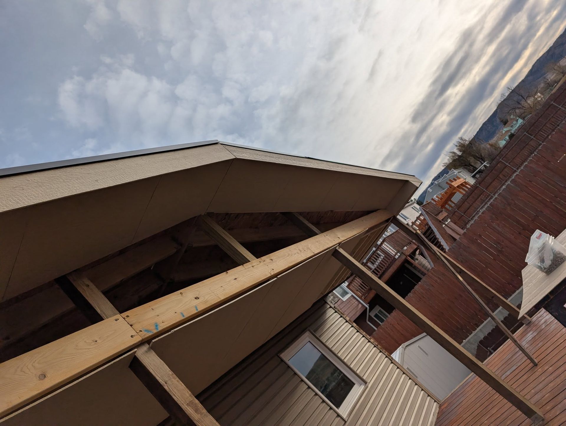 Tilted view of a brick building with a wooden beam and cloudy sky overhead