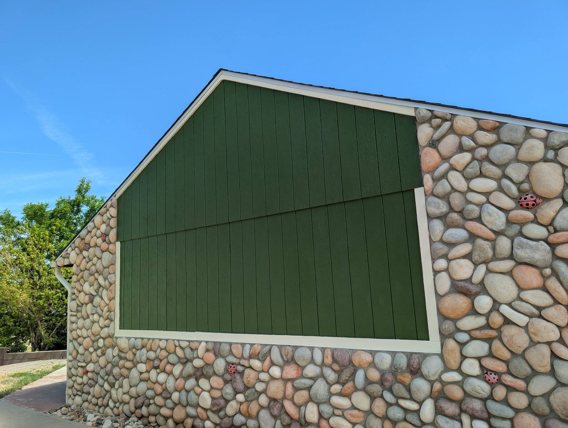 Stone building with a large green-painted wall and white trim under a blue sky