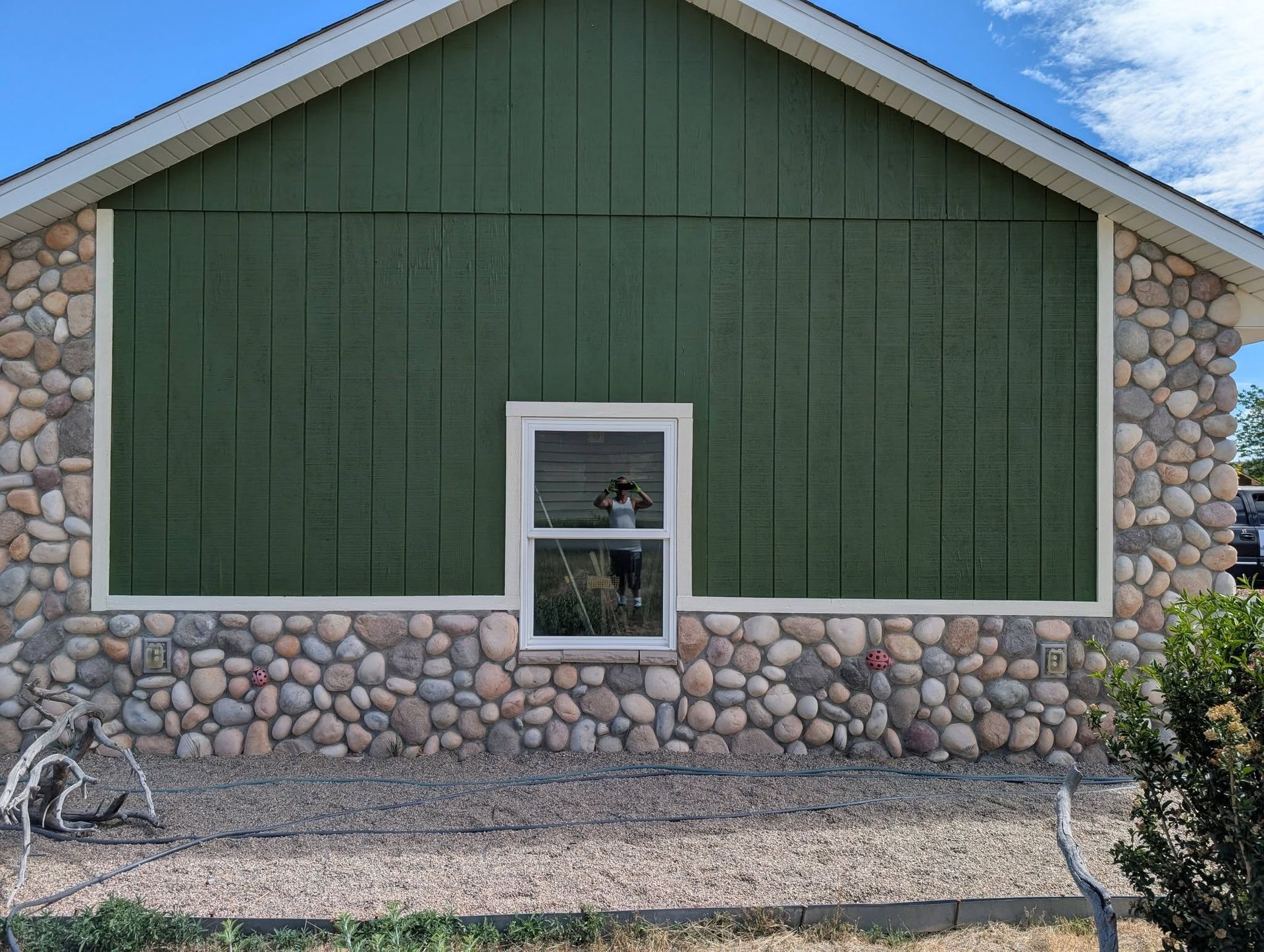 Green-sided house facade with stone trim and a small centered window