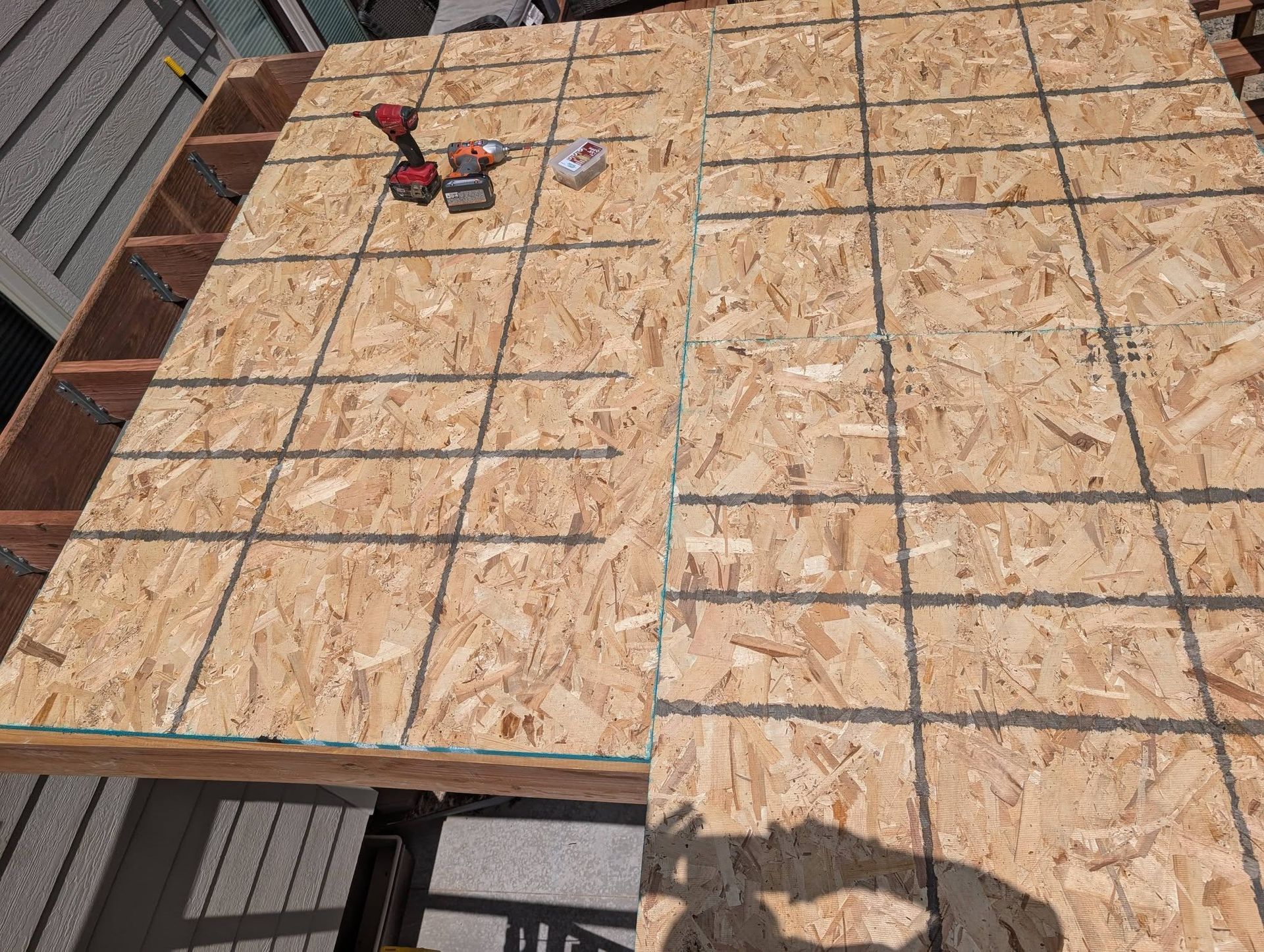 OSB roof sheathing under construction with a red cordless drill on the left side