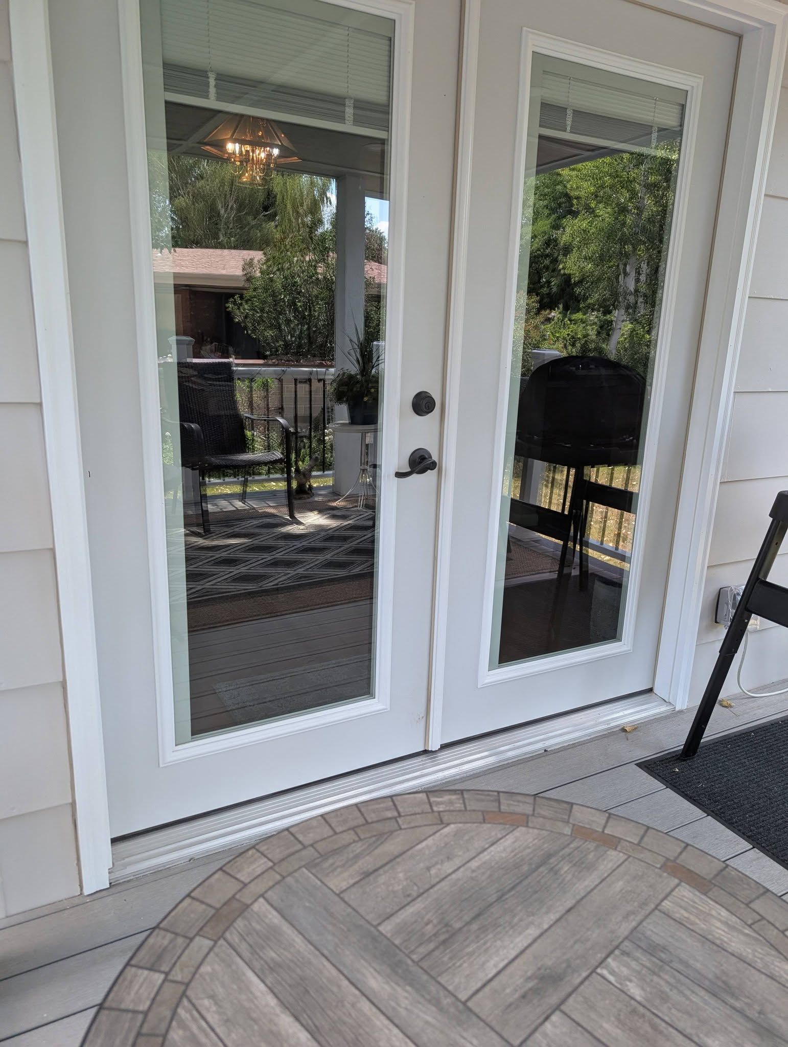 White double French doors with glass panes opening to a patio with a herringbone wood floor.