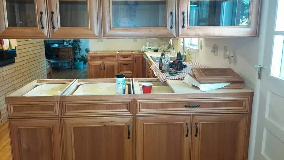 Kitchen with wooden cabinets, central island, sink, and a countertop cluttered with dishes and supplies.