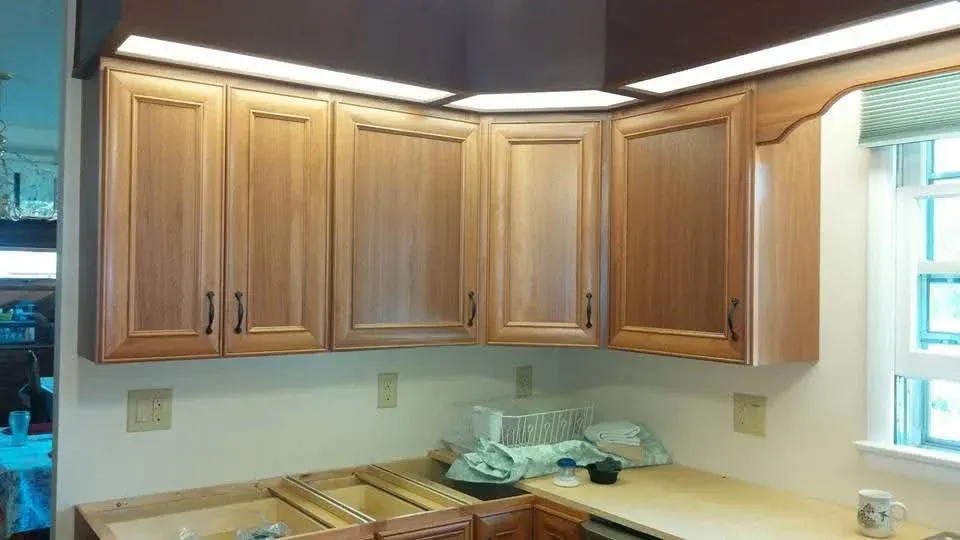 Kitchen with light wood cabinets, beige countertop, sink, and a bright window on the right.