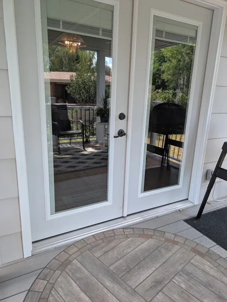White French doors on a patio with a curved stone walkway and outdoor seating visible through the glass