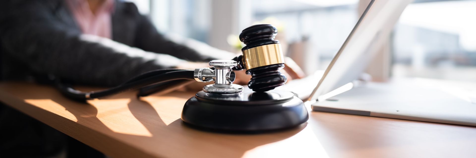 Judge’s gavel on desk beside a hand in a courtroom setting