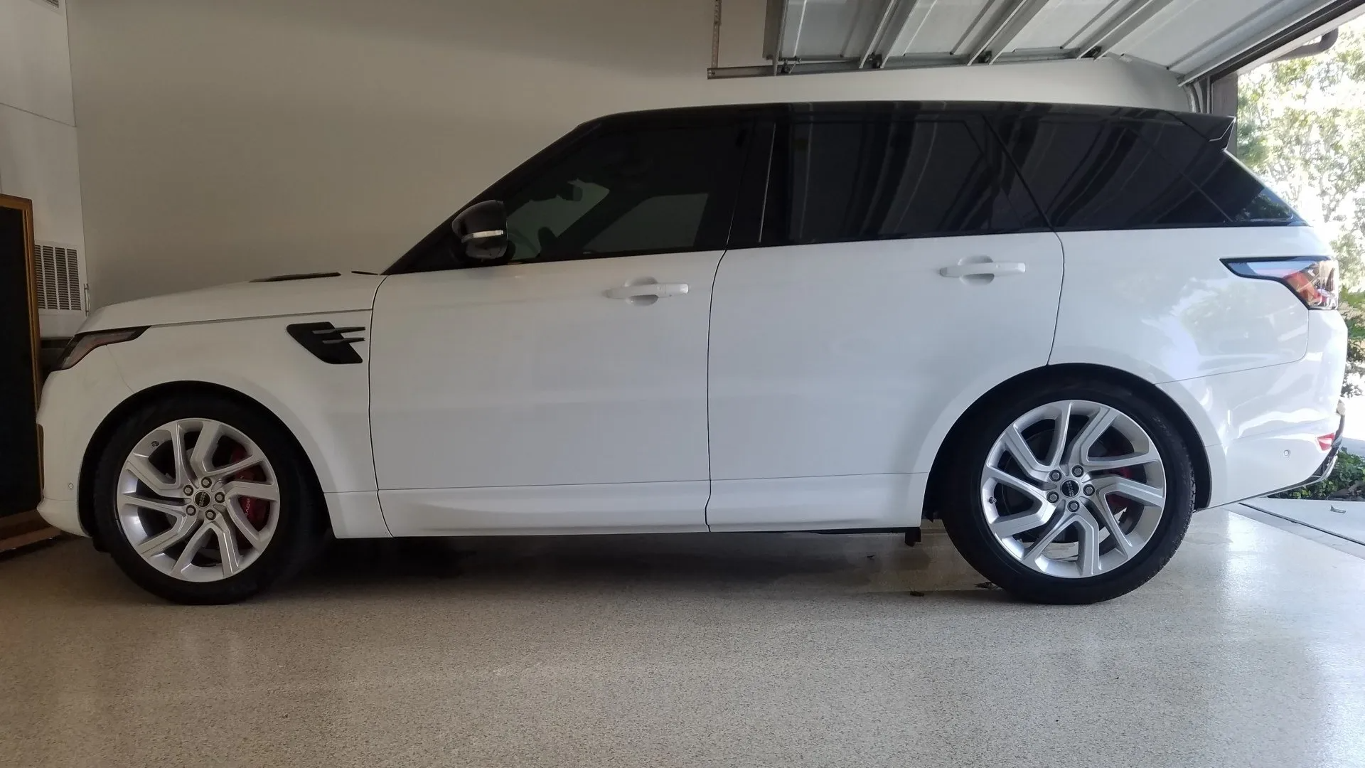 White Land Rover SUV parked inside a garage with a speckled floor.
