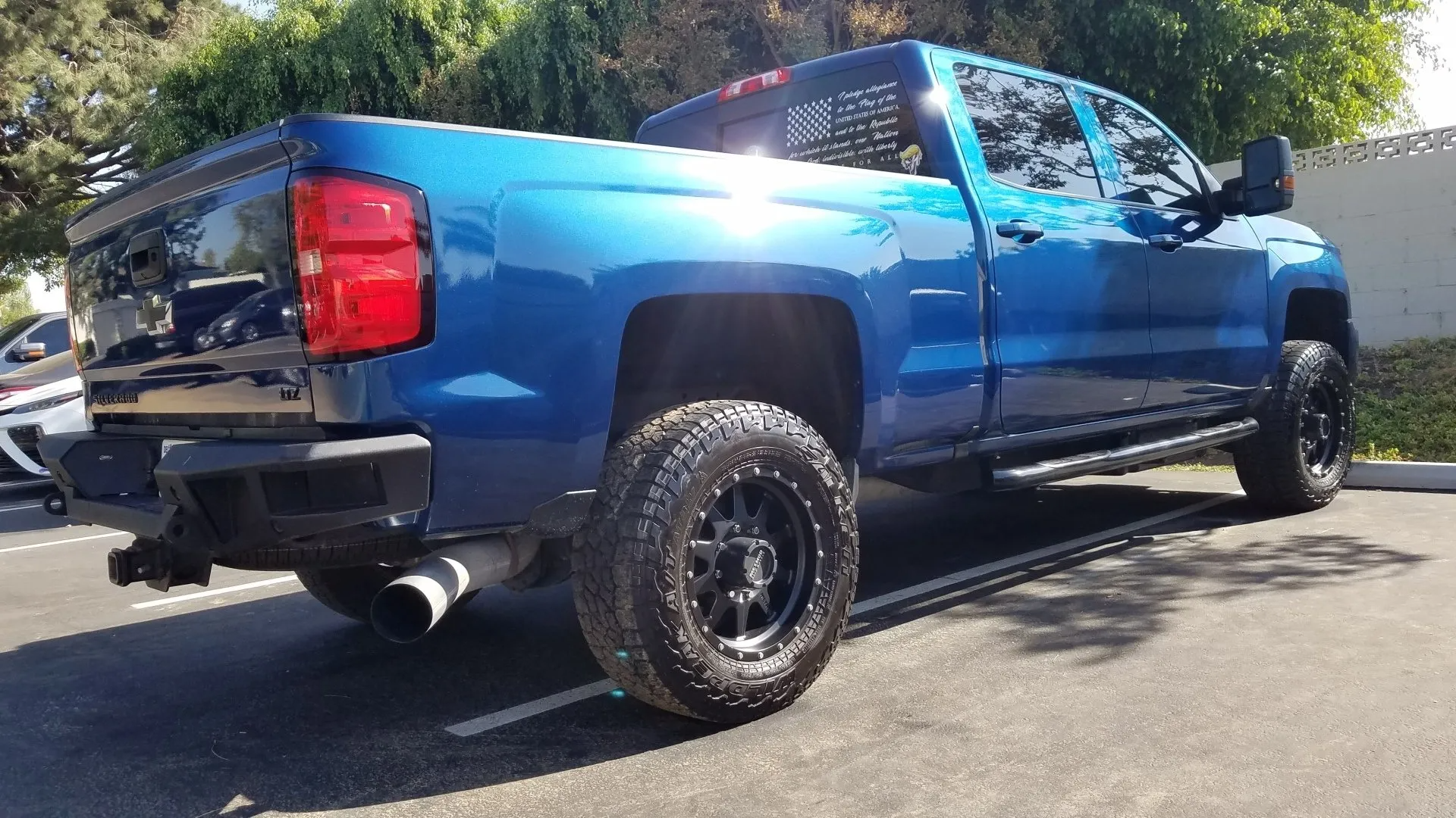 Blue pickup truck parked outdoors, with black wheels and exhaust pipes.