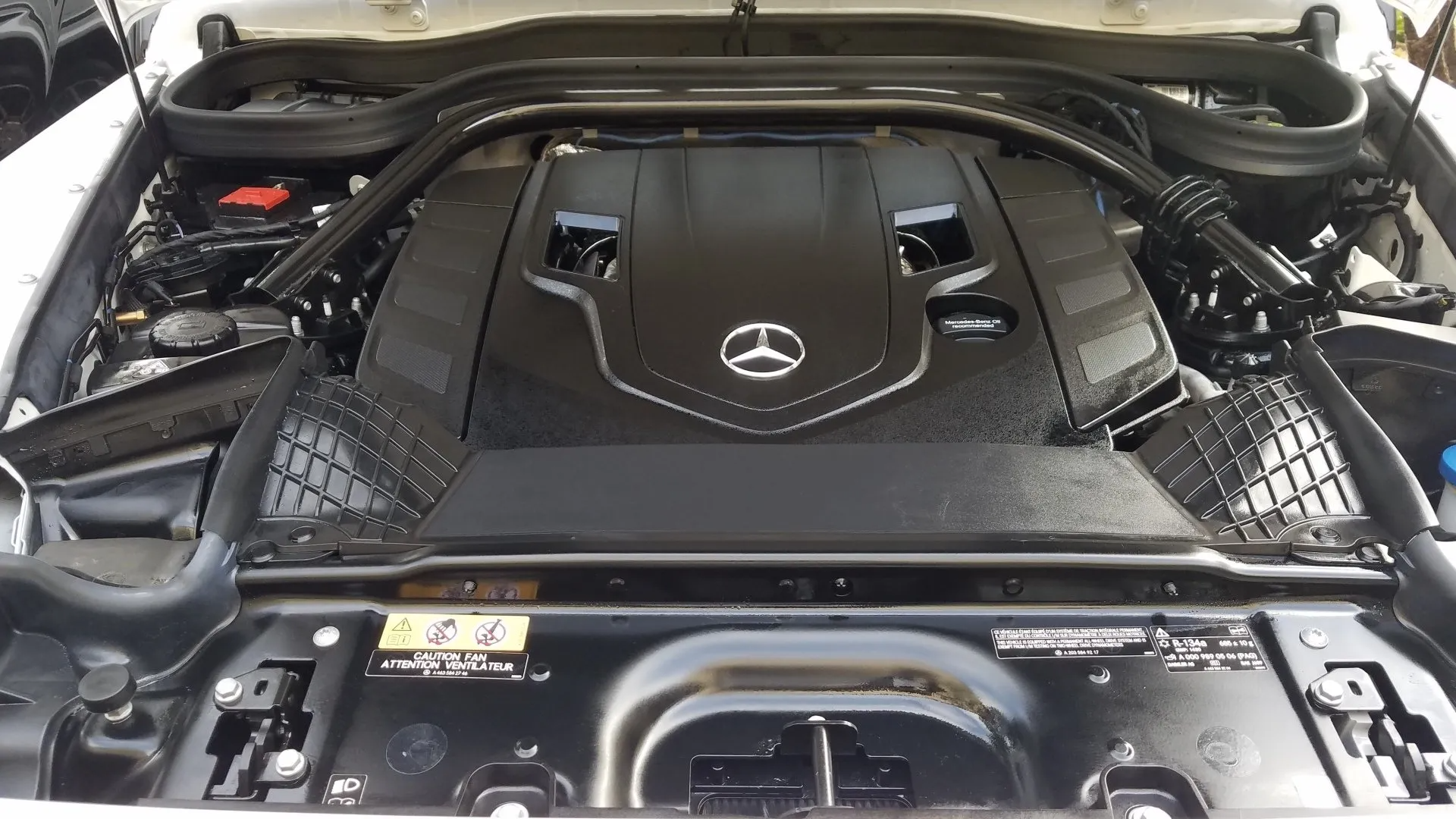 Engine compartment of a black Mercedes-Benz car with its hood open.