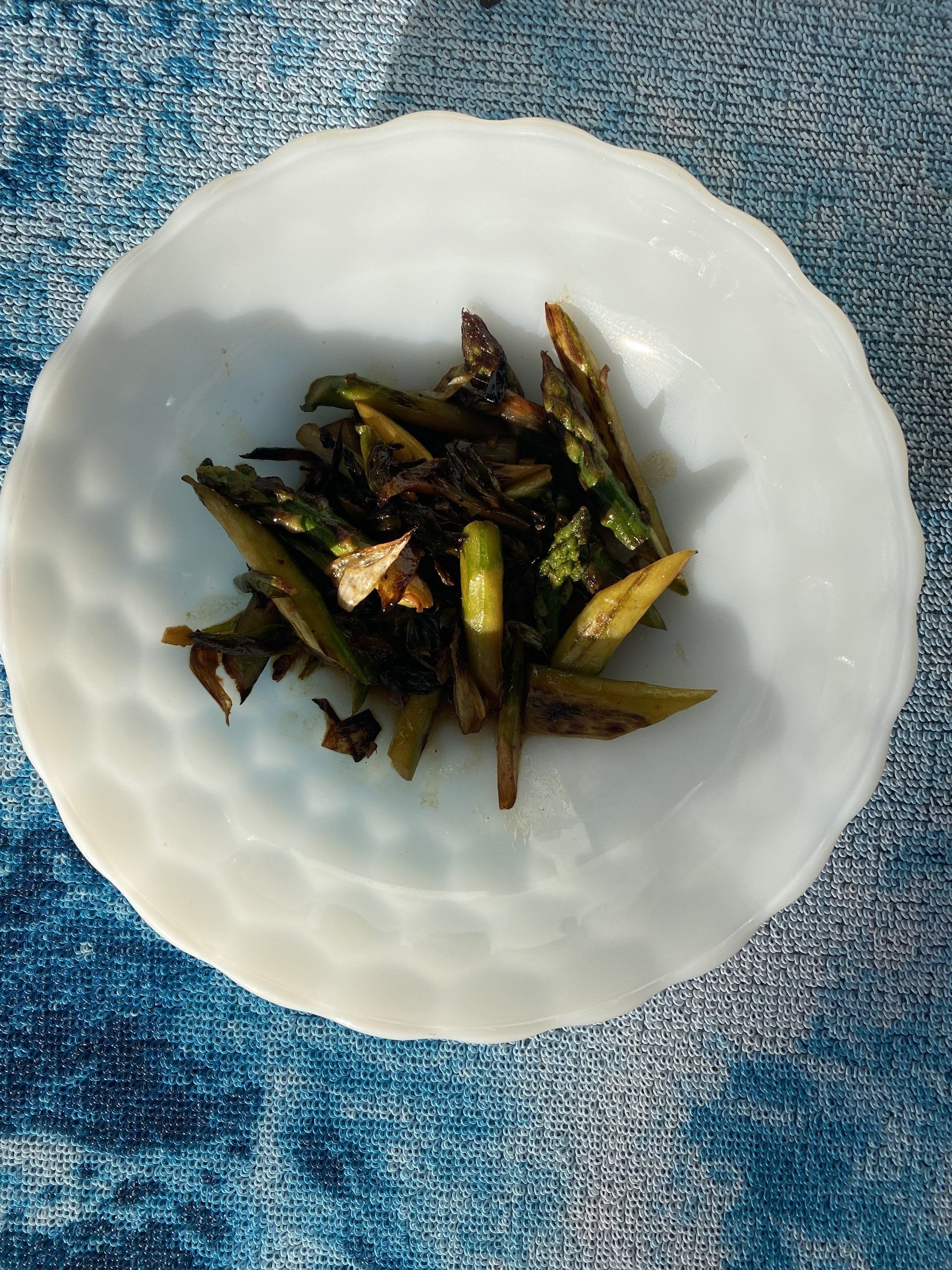 A small white bowl filled with vegetables is on a table.