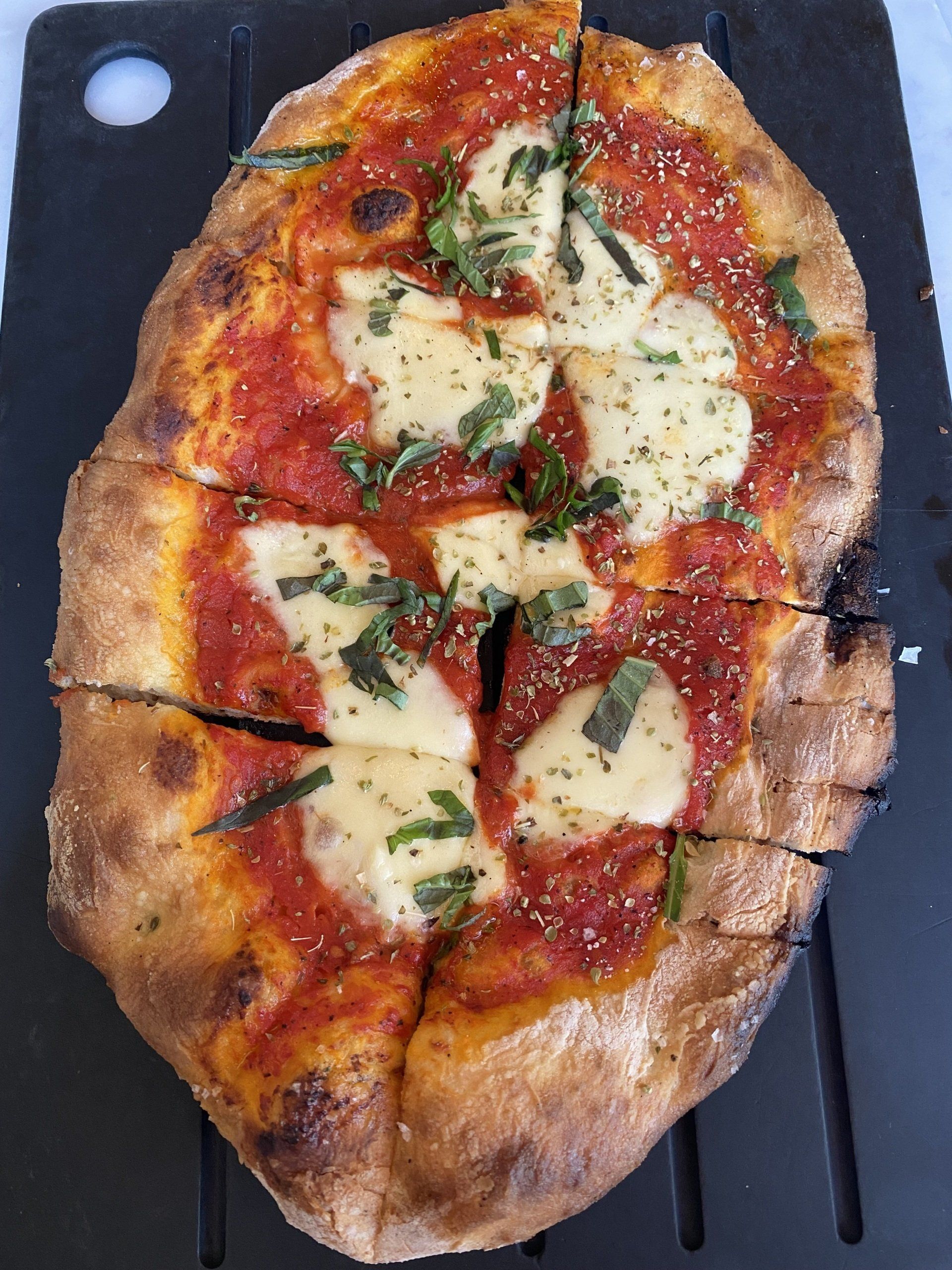 A pizza with tomato sauce and cheese on a cutting board
