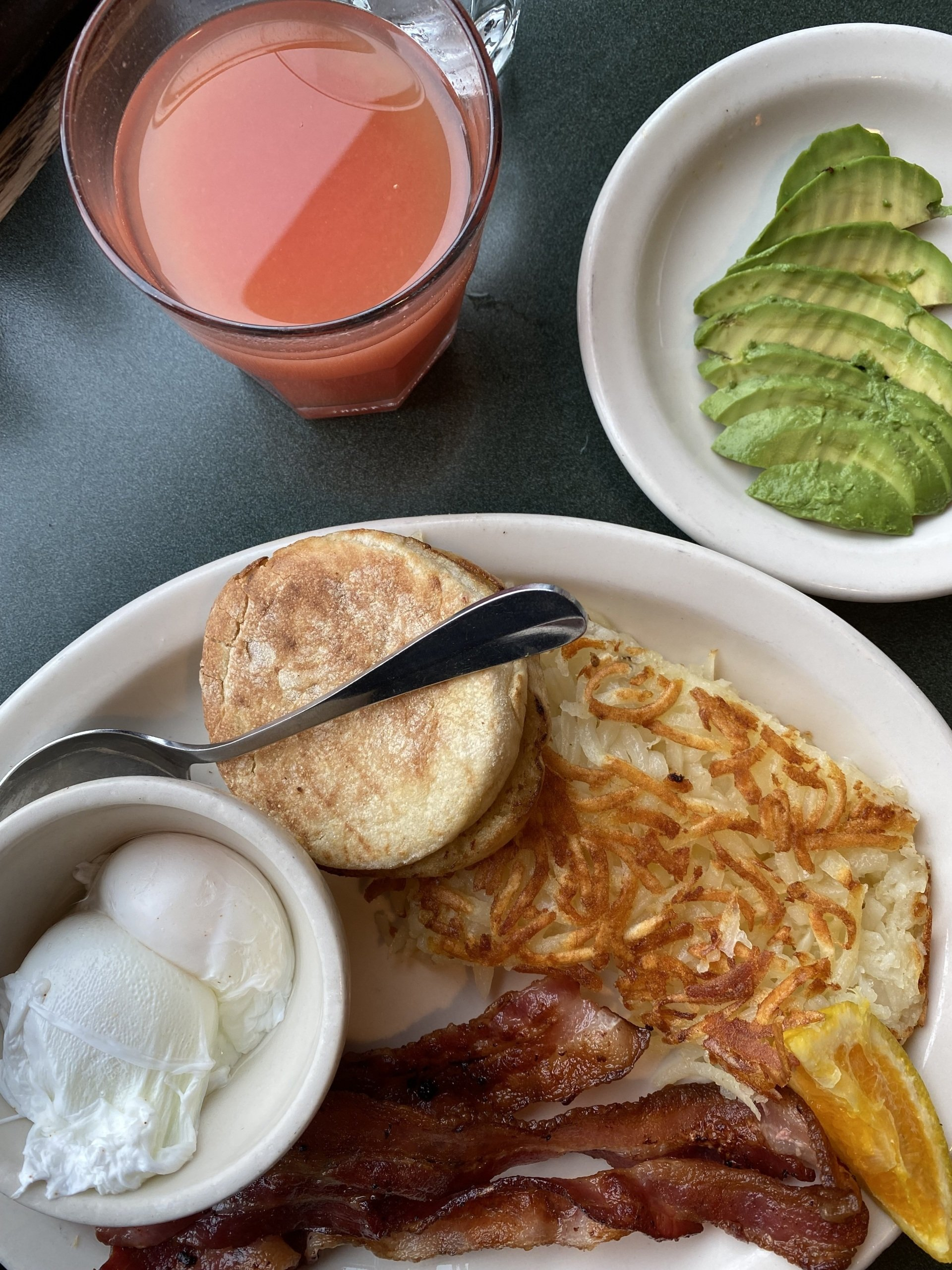 A plate of food with bacon eggs and avocado on a table