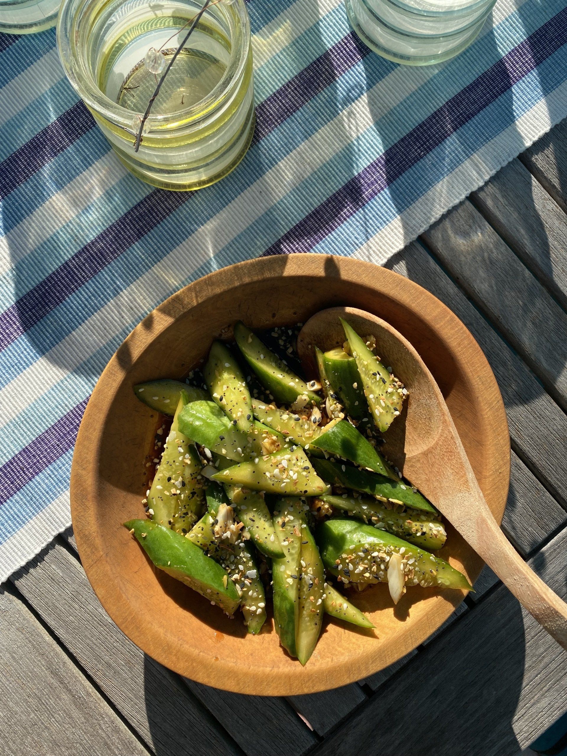 A wooden bowl filled with asparagus and a wooden spoon on a table.