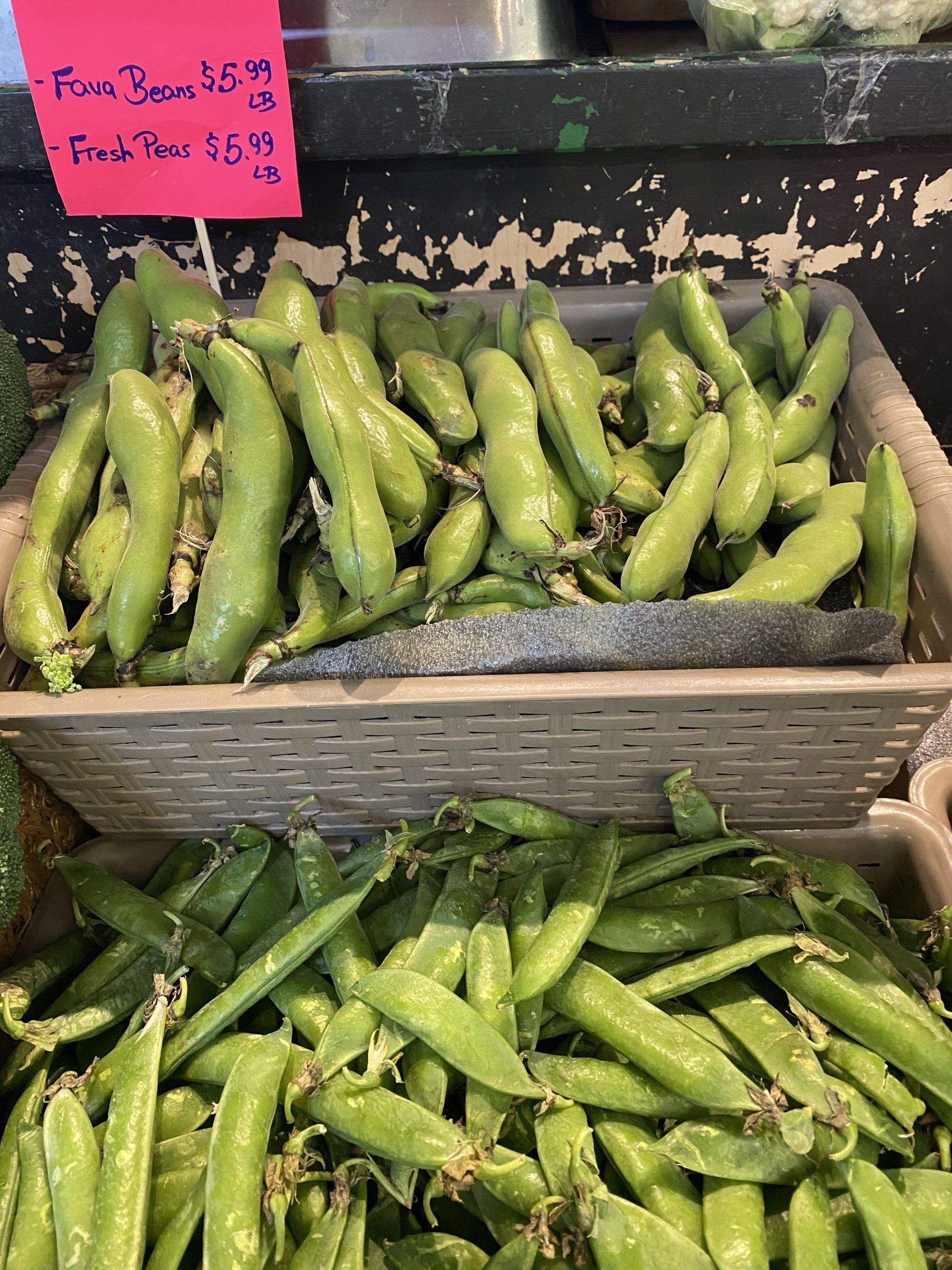 A basket of green peas is sitting on a counter.