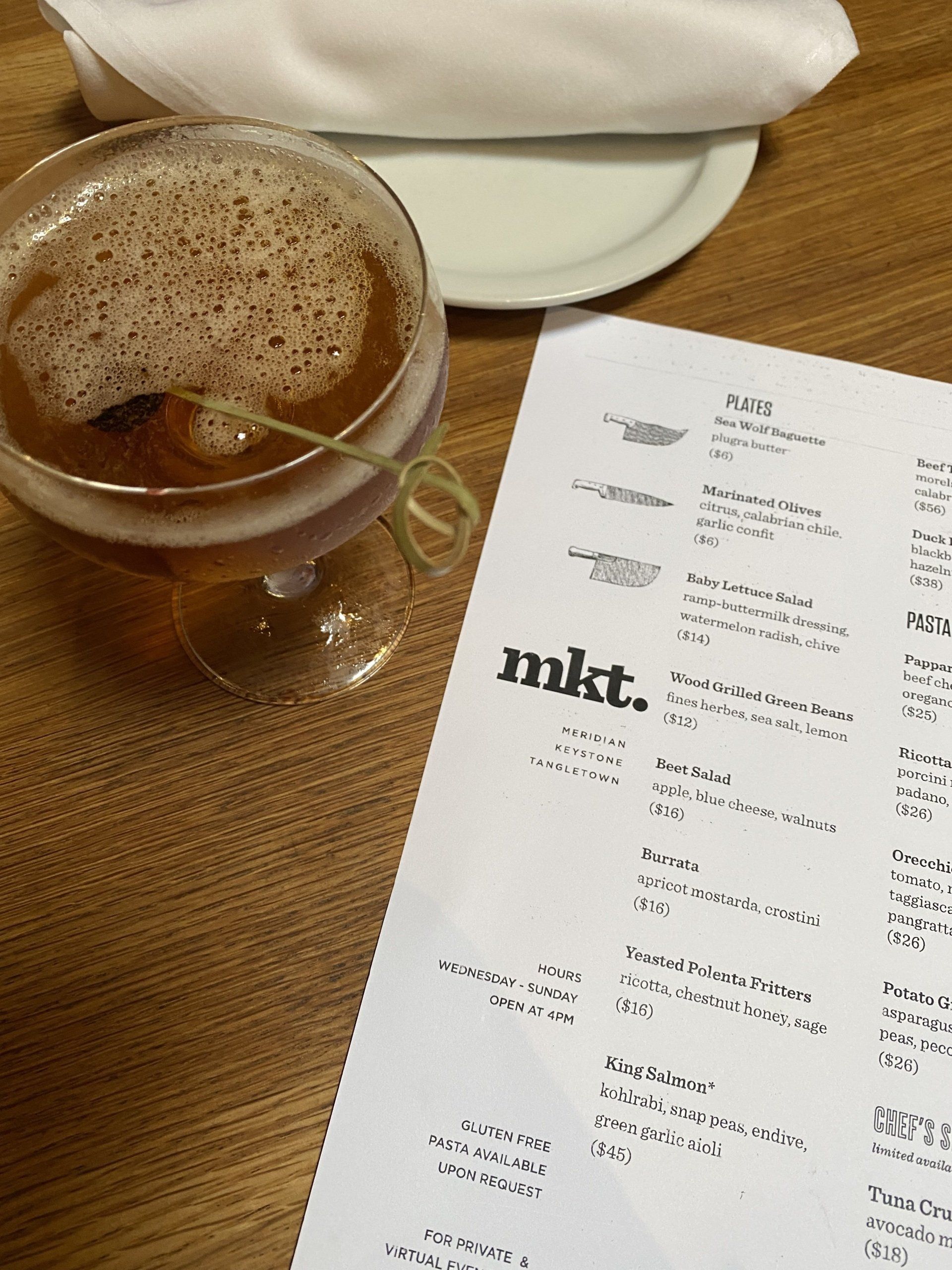 A drink in a glass next to a menu that says nkt