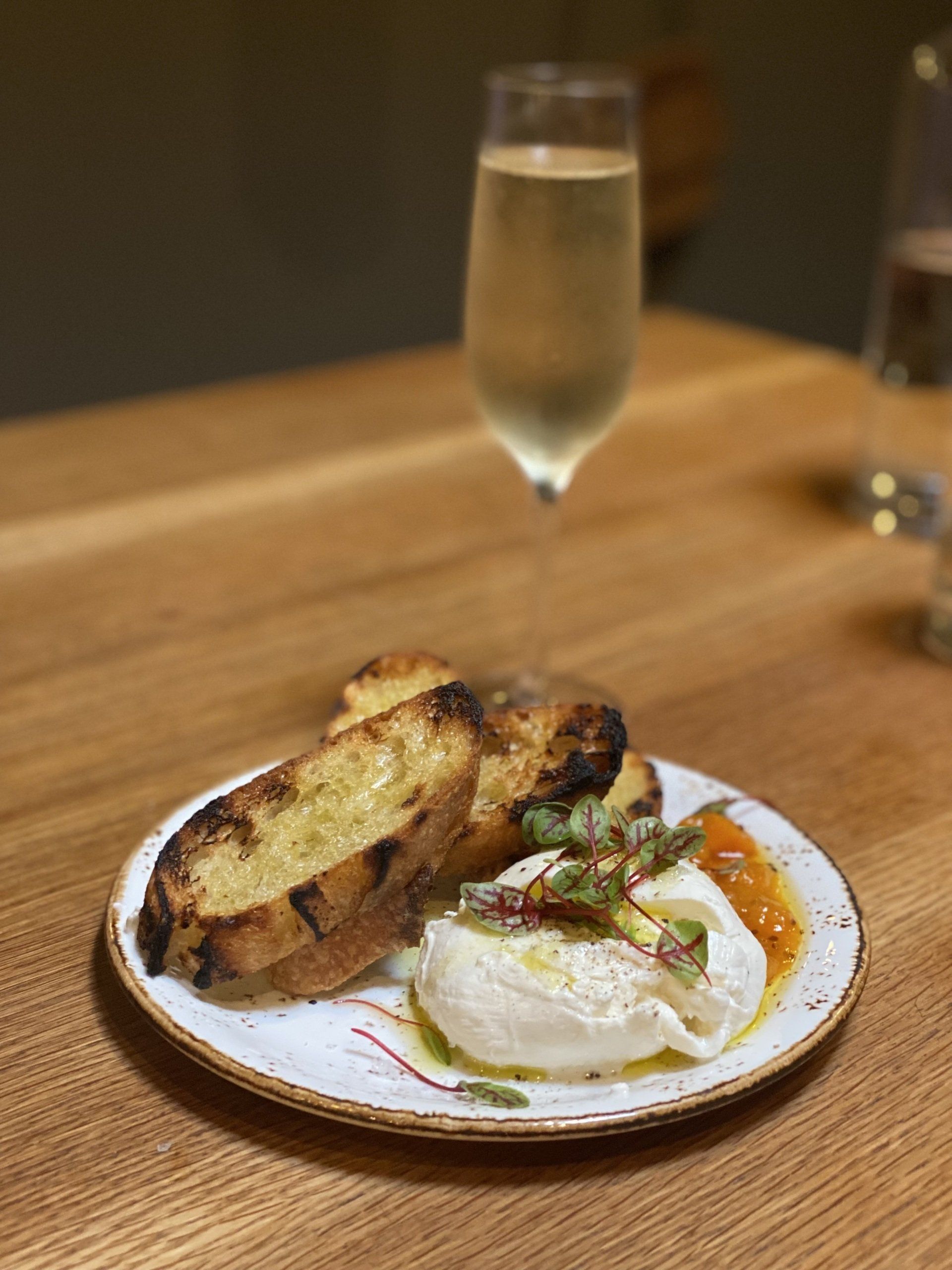 A plate of food and a glass of wine on a wooden table.