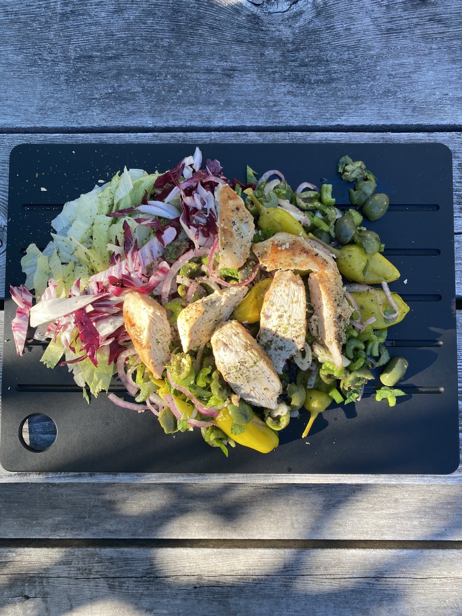 A plate of food with meat and vegetables on a wooden table.