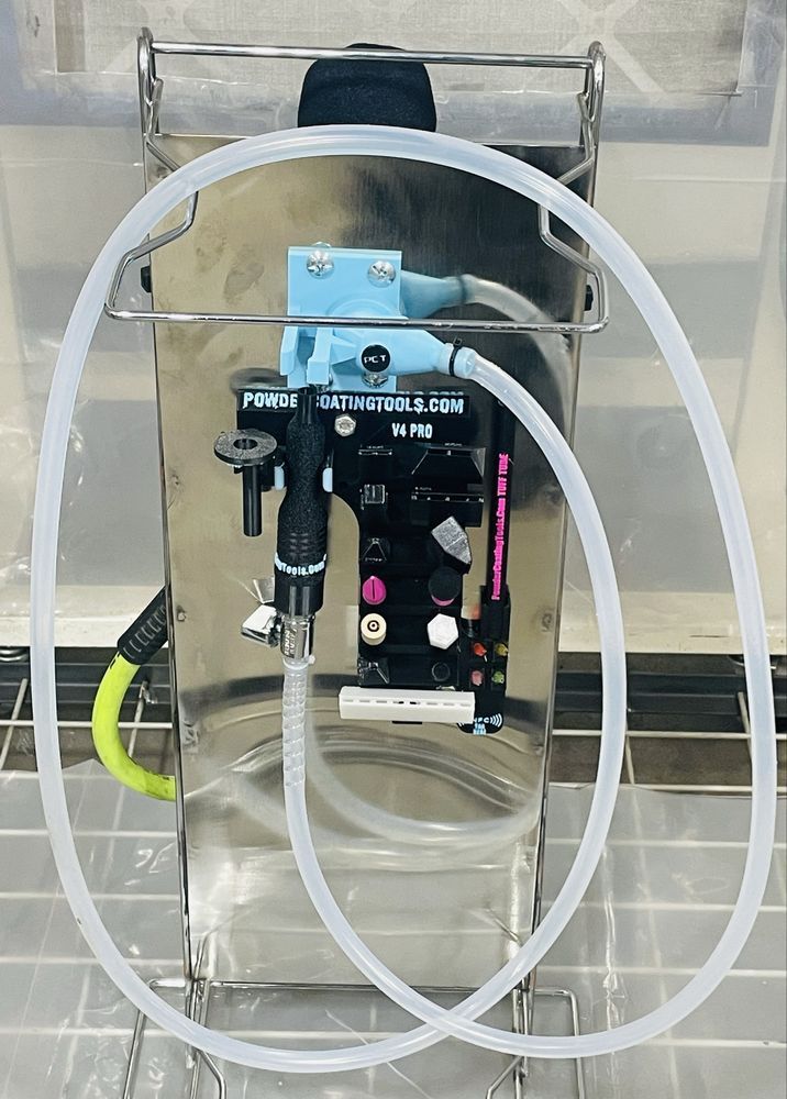A black and light blue mechanical sprayer nozzle attached to a metal stand with clear plastic tubing, inside a room.