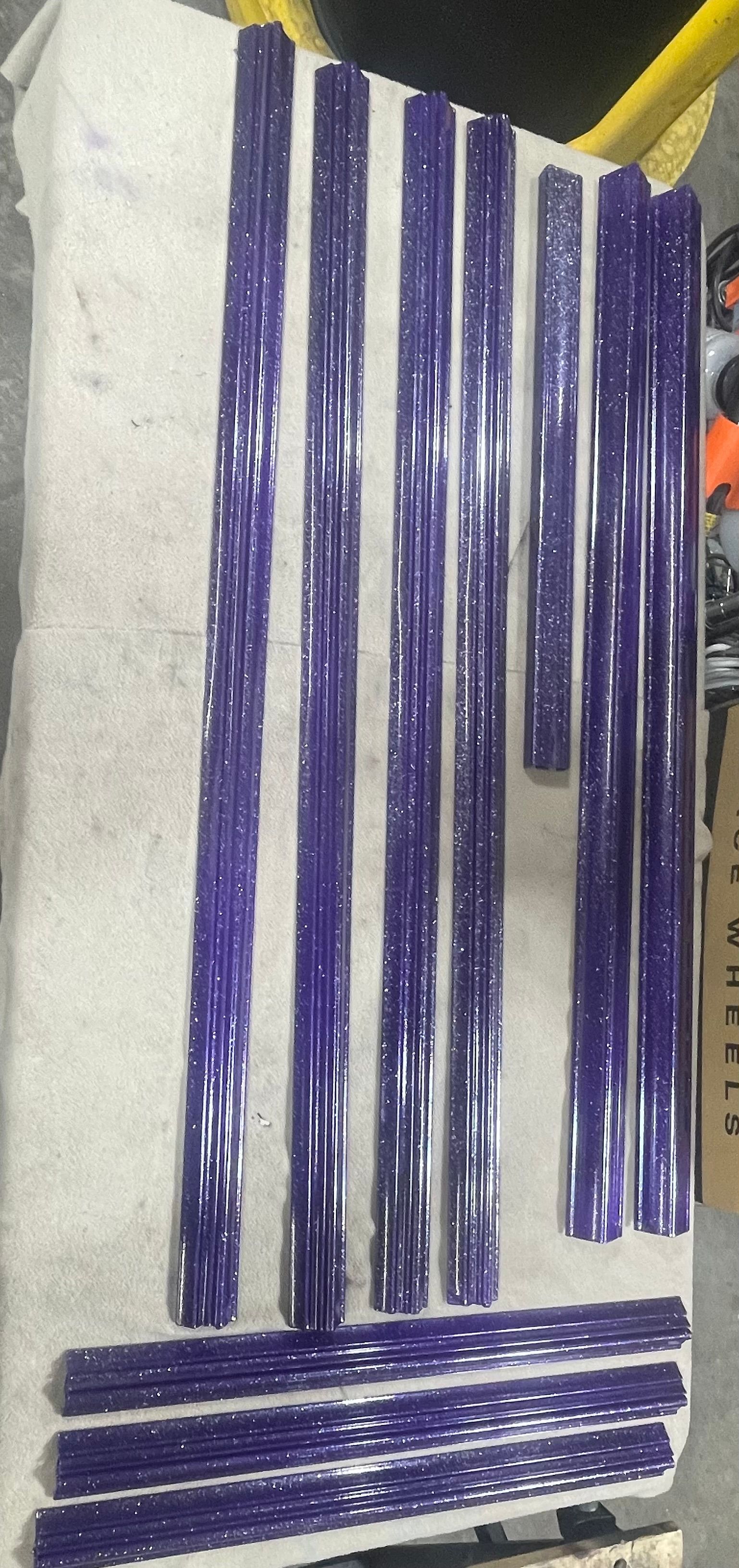 A set of purple, plastic-wrapped, ribbed construction poles arranged on a white surface.
