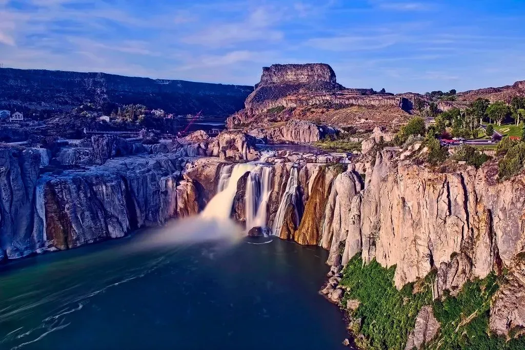 Waterfall plunging into a deep blue canyon beneath rocky cliffs at sunset