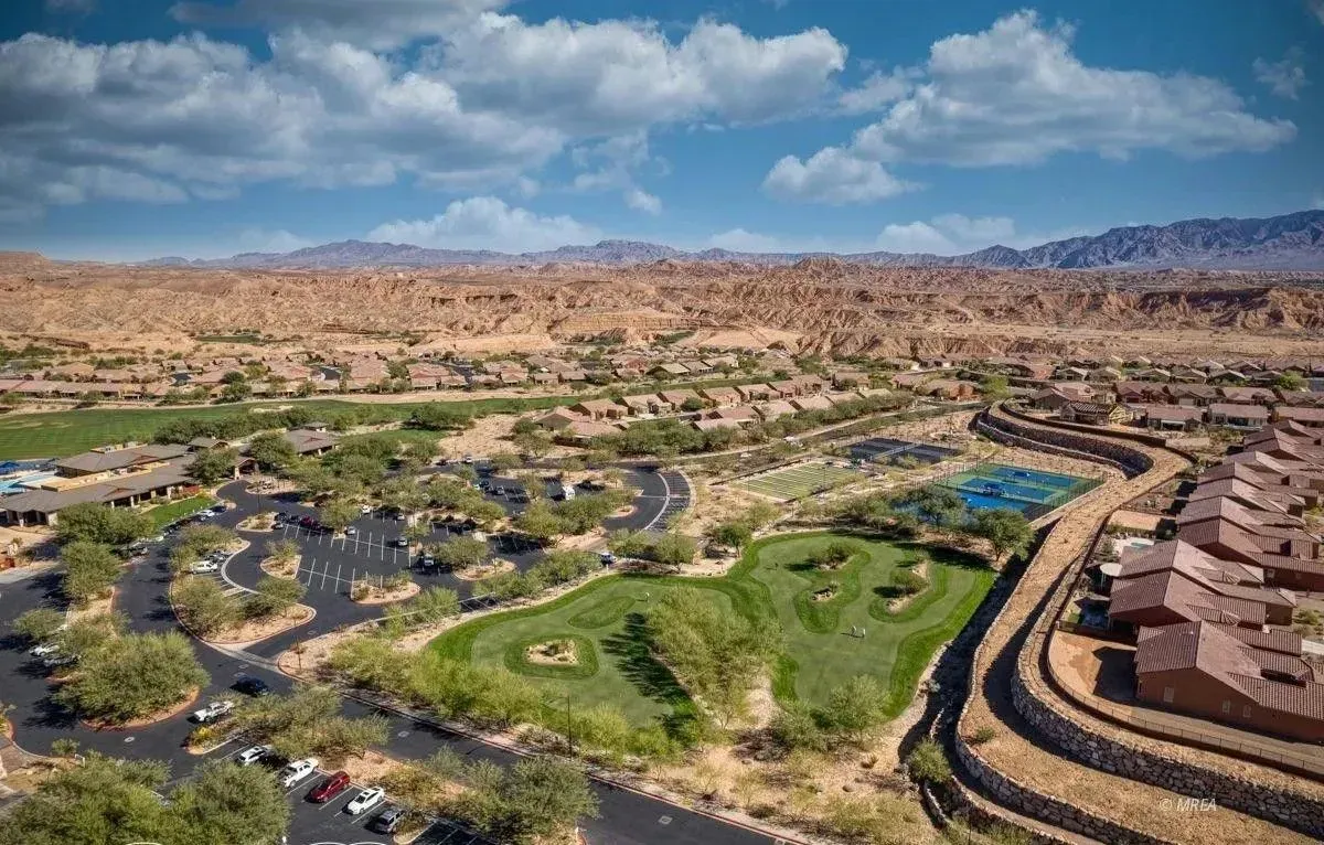 Aerial view of a desert resort with green lawns, pools, and tan buildings under a blue sky