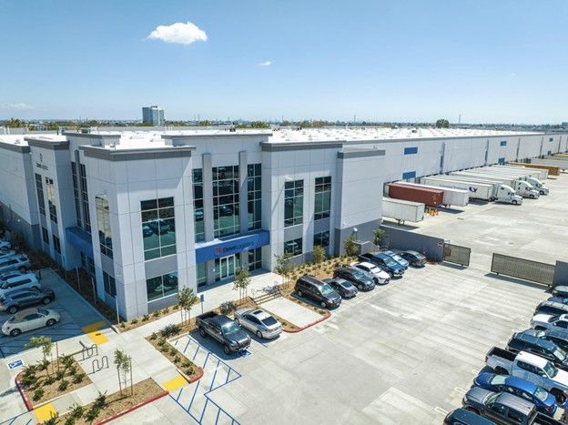 Industrial warehouse complex with parked cars and loading docks on a sunny day