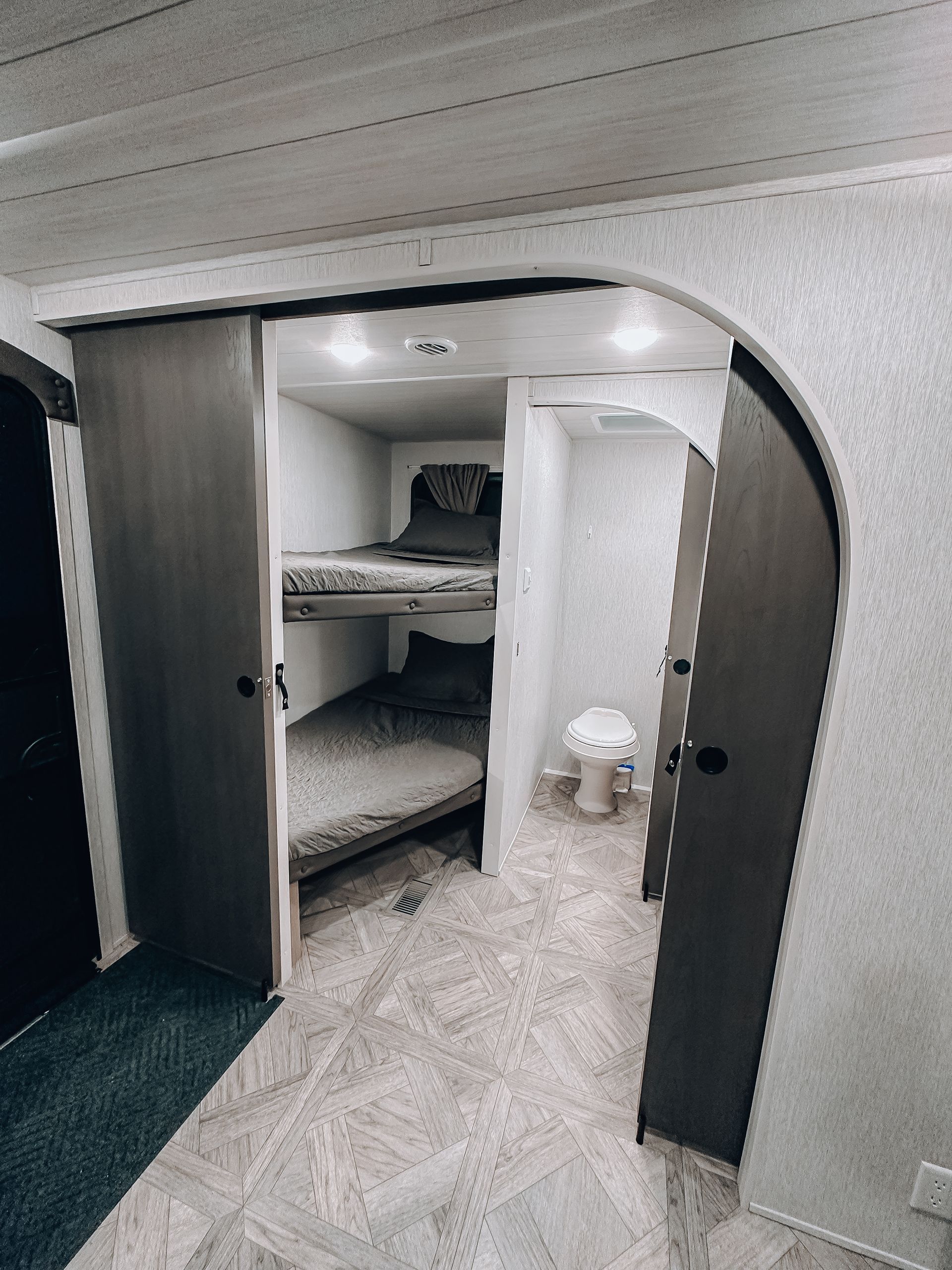 Small bunk room with white walls, two open doors, and built-in beds under a curved ceiling.