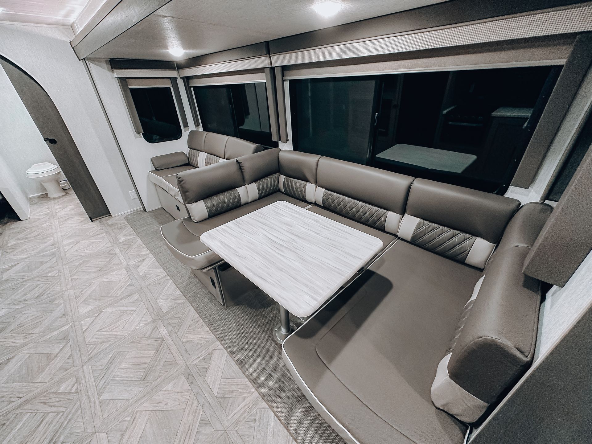 Modern RV lounge with gray sectional seating and a small white table by large windows