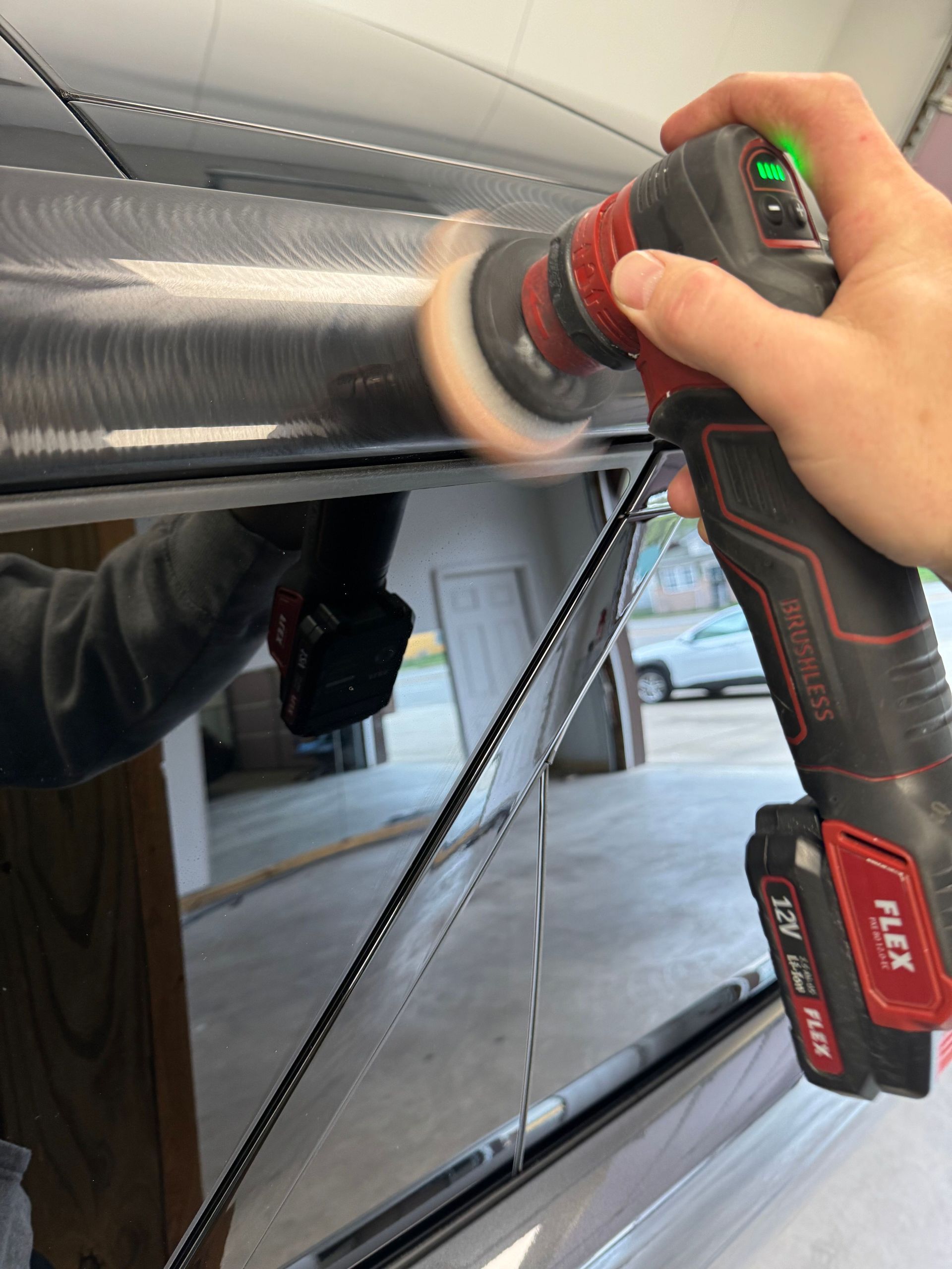 A person is polishing a car door with a polisher.