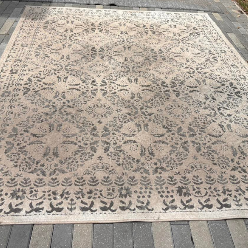 Beige and gray patterned outdoor rug on a brick patio.